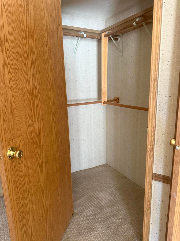 Interior closet featuring wood-finish shelving and hanging rods