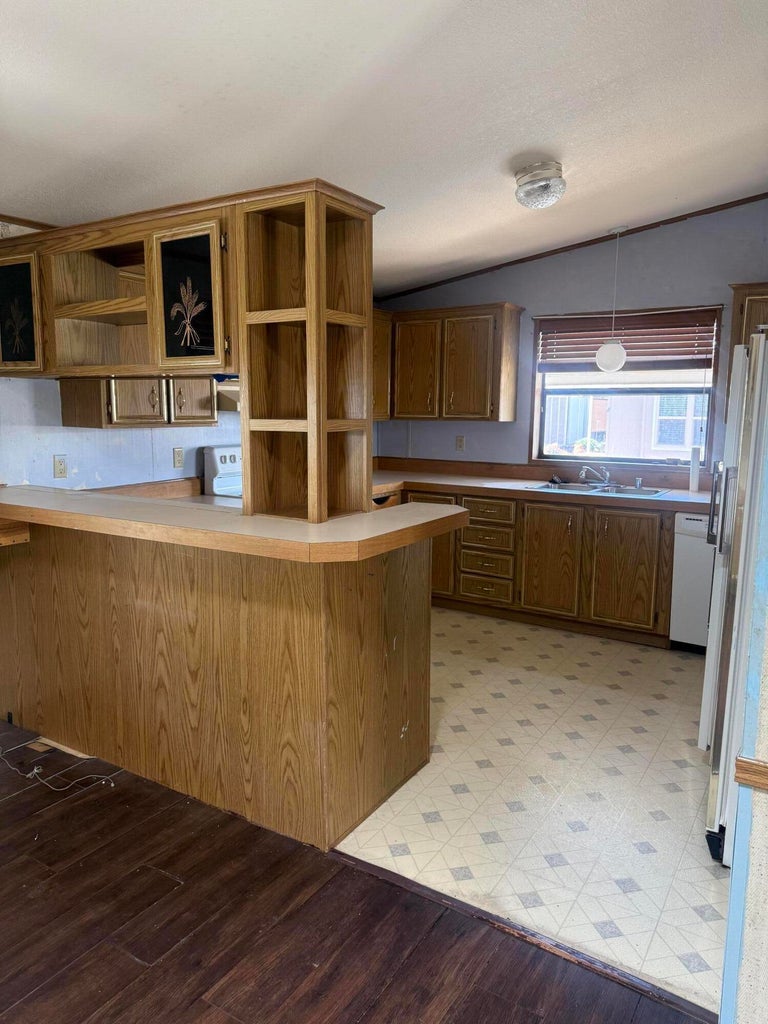 Kitchen featuring wood-finish cabinetry, a built-in breakfast bar, a double basin sink, light-toned flooring with a geometric pattern, and dark wood-finish flooring