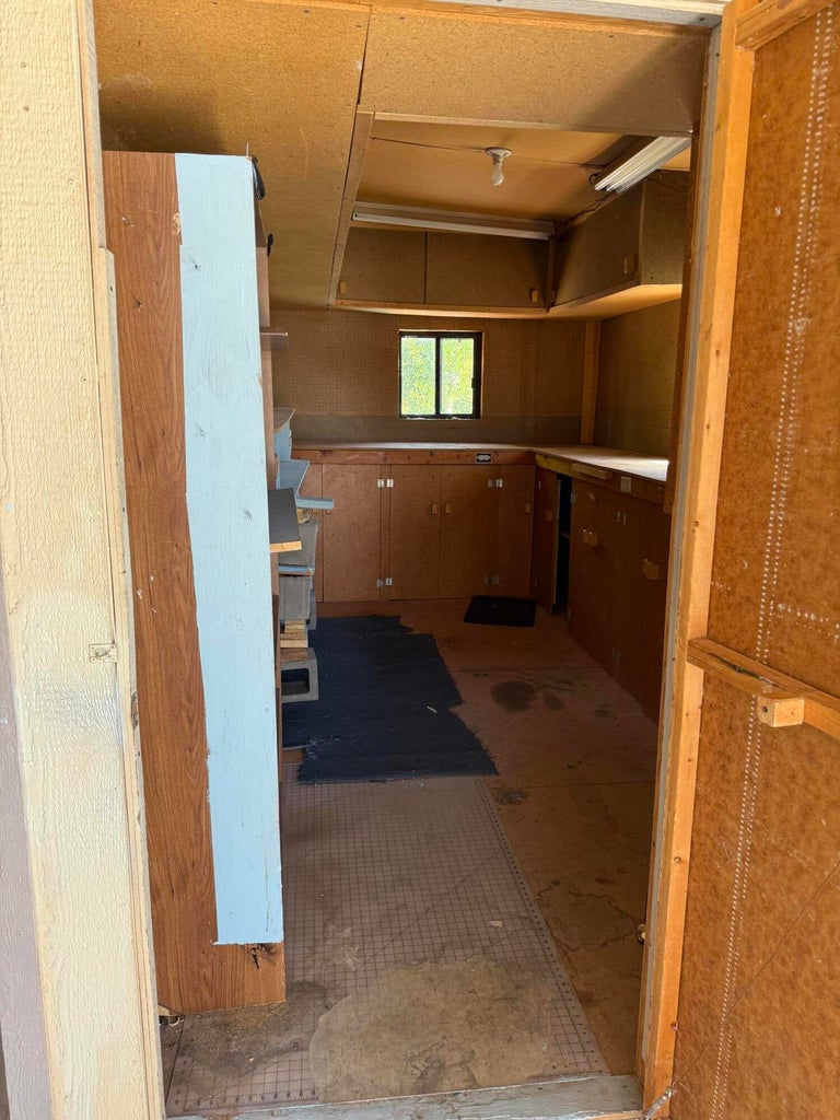 Utility room featuring built-in cabinetry, overhead storage, and a single window