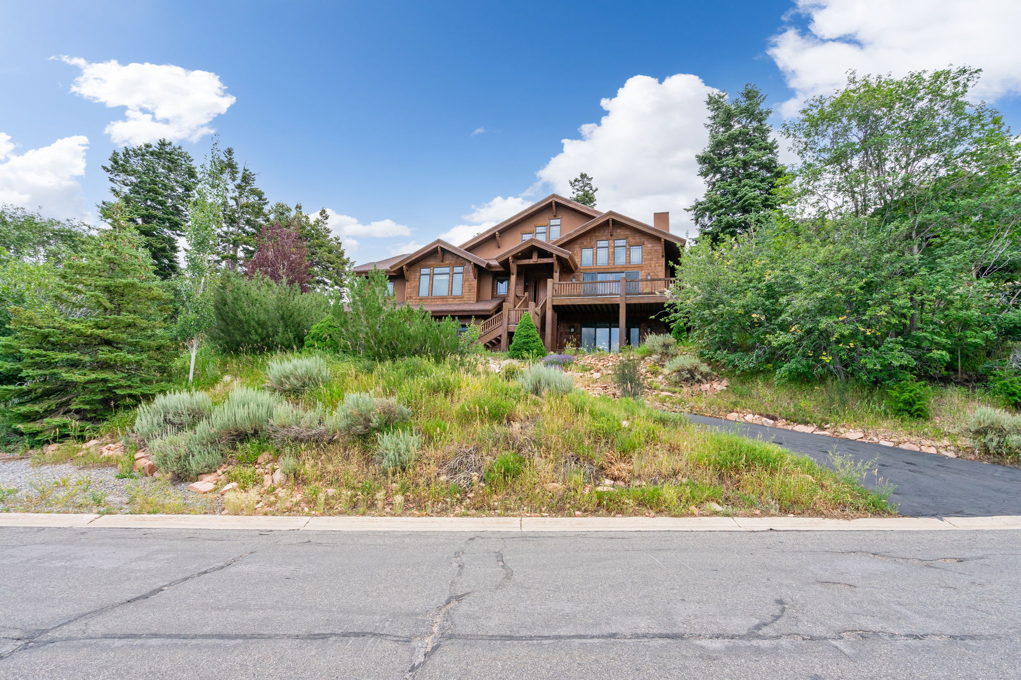 Multi-level wood-sided residence featuring multiple decks, an expansive array of windows, and a prominent chimney