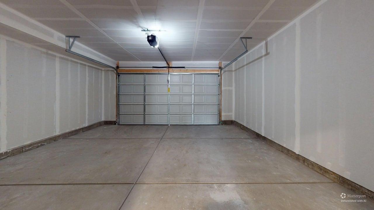 Spacious two-car garage featuring a sectional overhead door, concrete flooring, and an automatic garage door opener