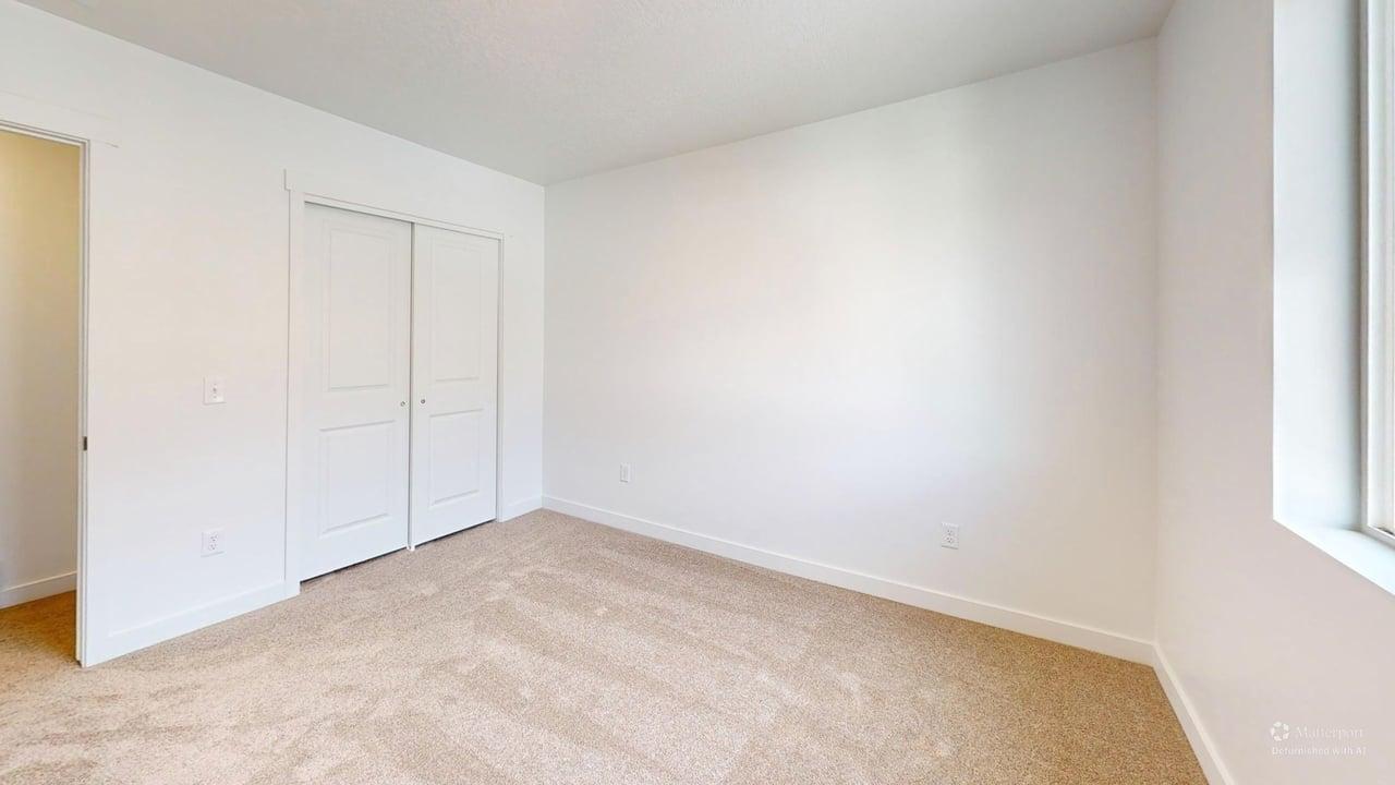 Carpeted room featuring a double-door closet, white trim, and a window for natural light