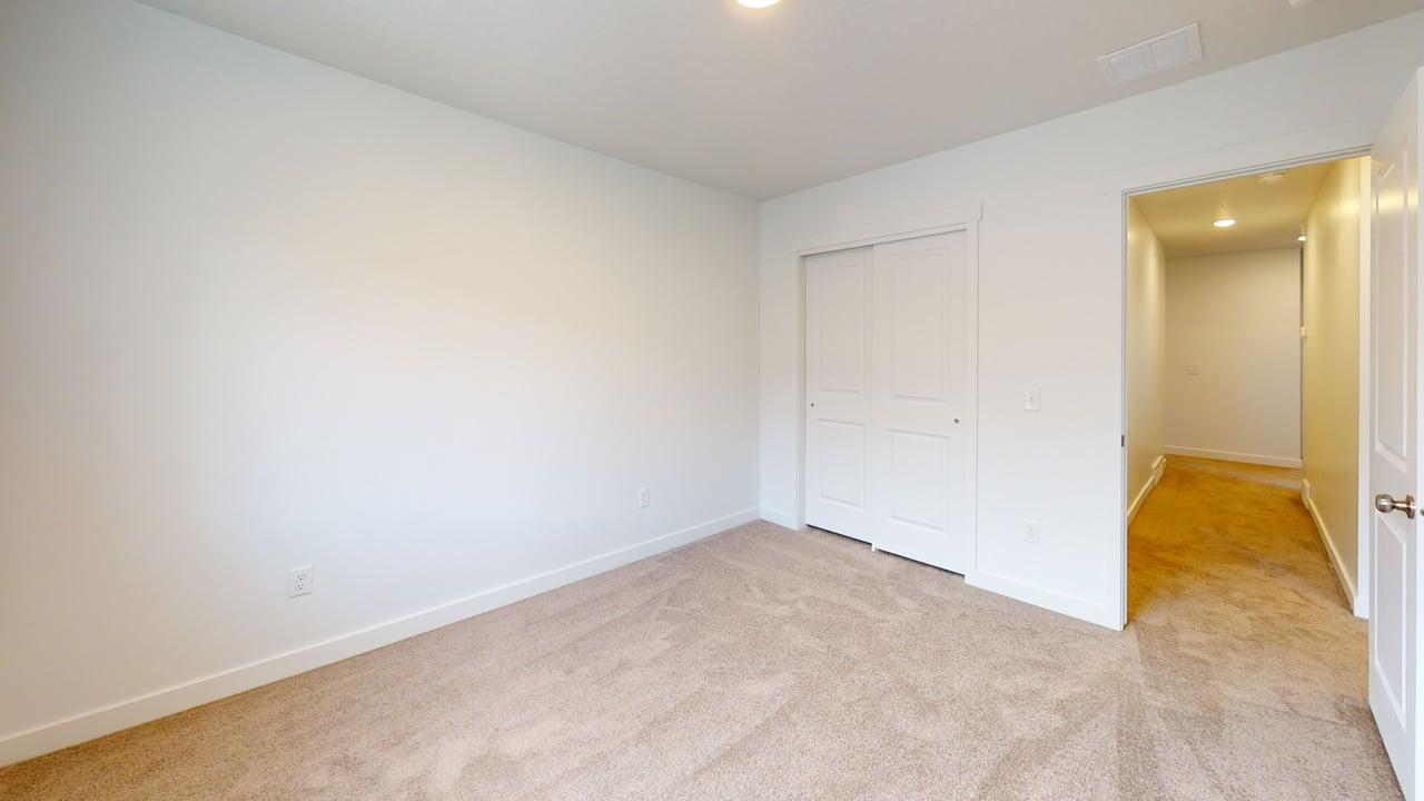 Carpeted room with white walls, baseboards, and a sliding closet door