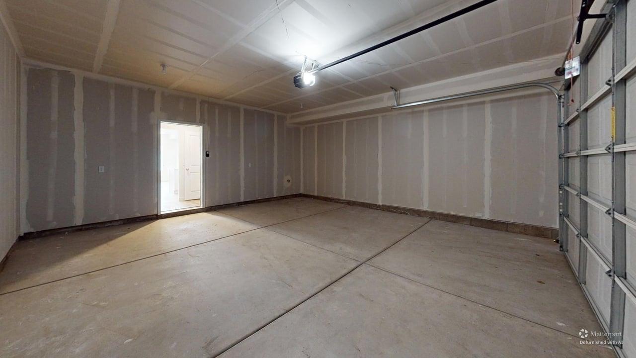 Spacious garage with concrete flooring, automatic garage door opener, and unfinished gypsum board walls