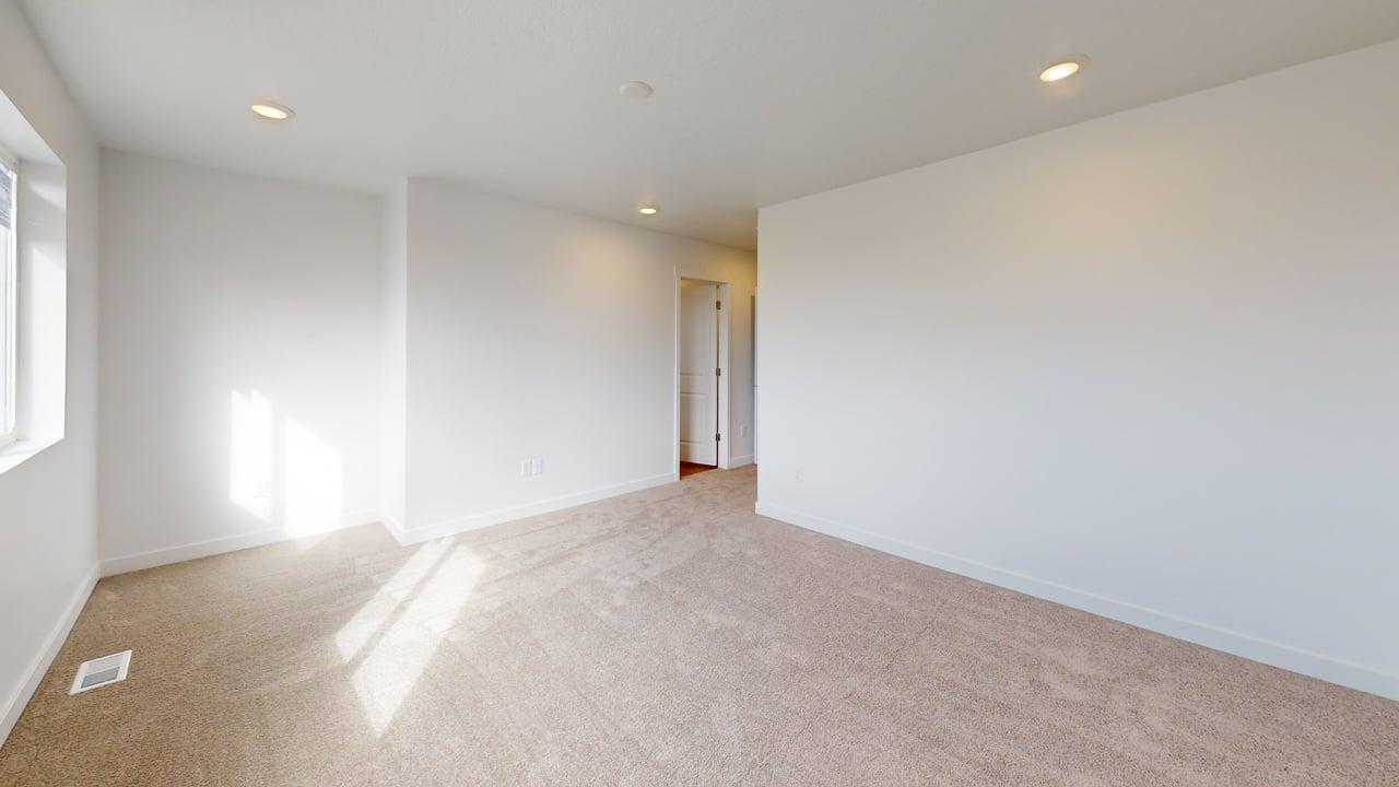 Spacious room featuring neutral carpeting, white walls, recessed ceiling lighting, and a white-trimmed window
