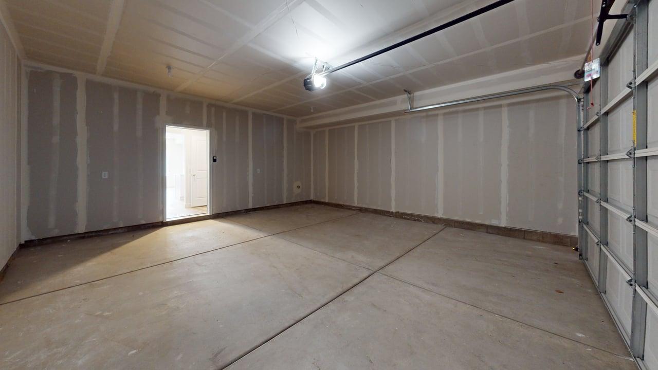 Spacious garage with concrete flooring, overhead lighting, and an automatic garage door opener mechanism