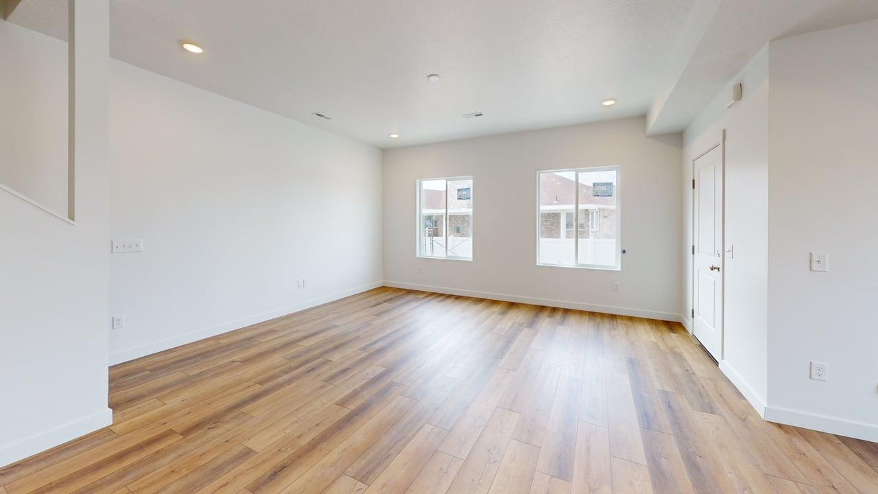Spacious room featuring wide plank wood-finish flooring, recessed lighting, and two large windows