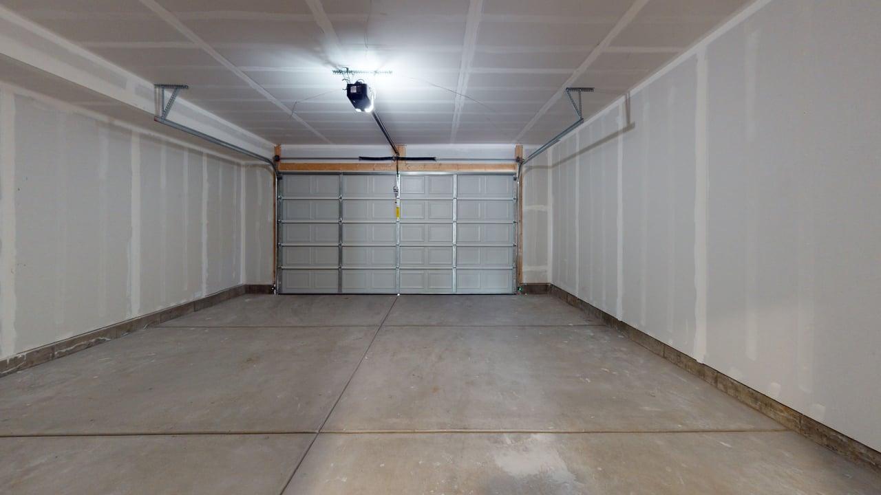 Spacious garage with a sectional garage door, concrete flooring, and an automatic garage door opener