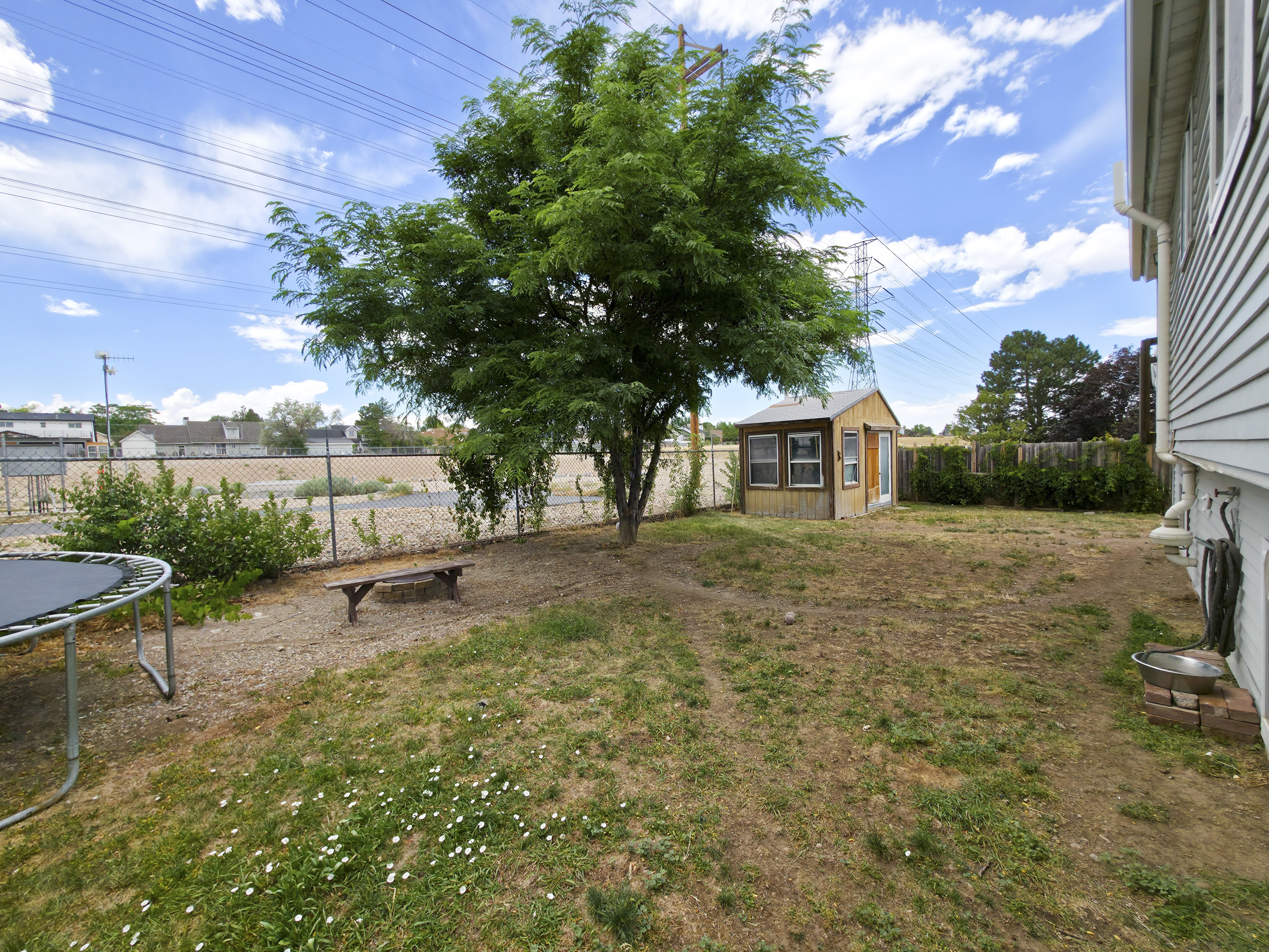 Back yard: open behind, firepit at center, shed on right.