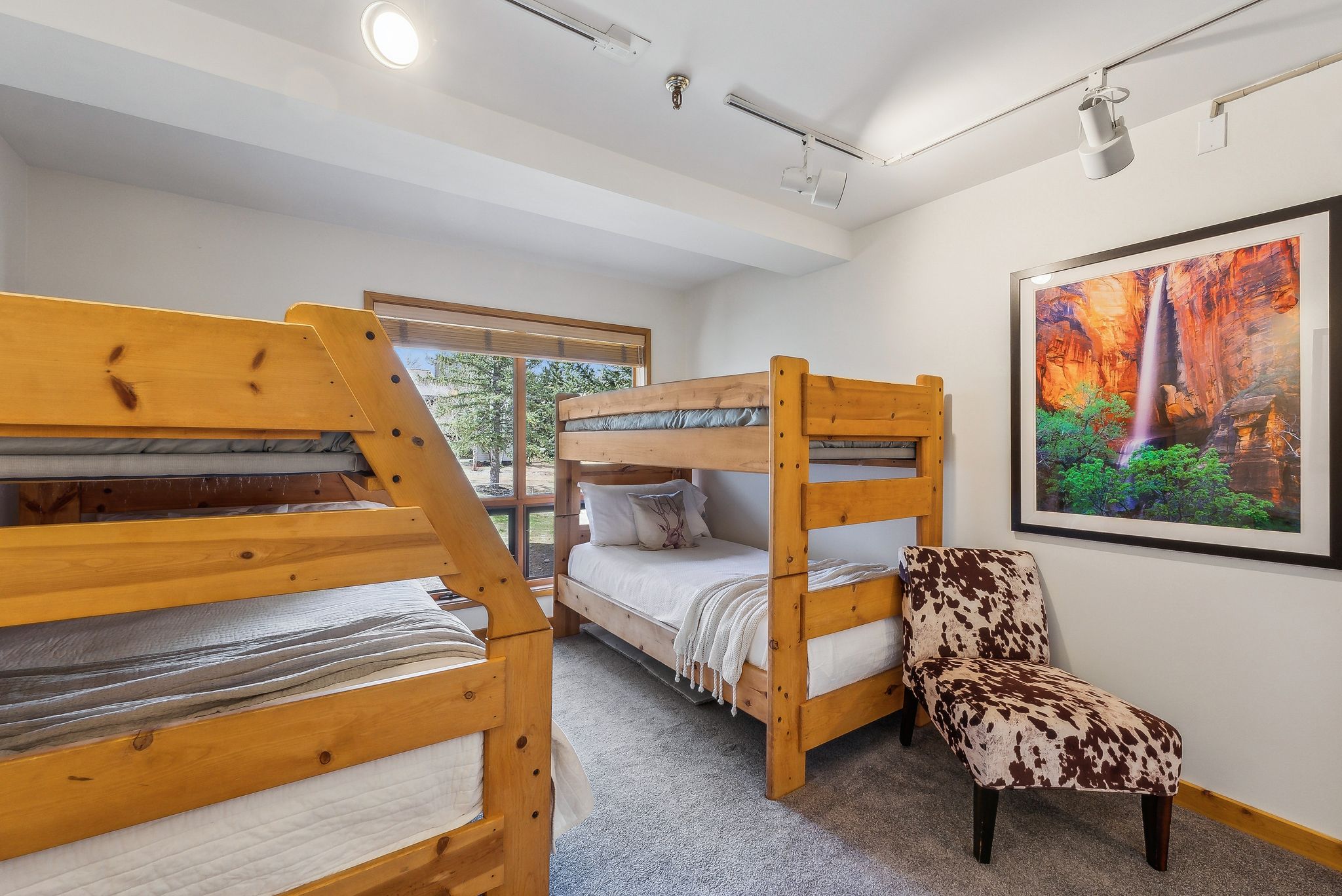 Room featuring two wood bunk beds, track lighting, and a large window