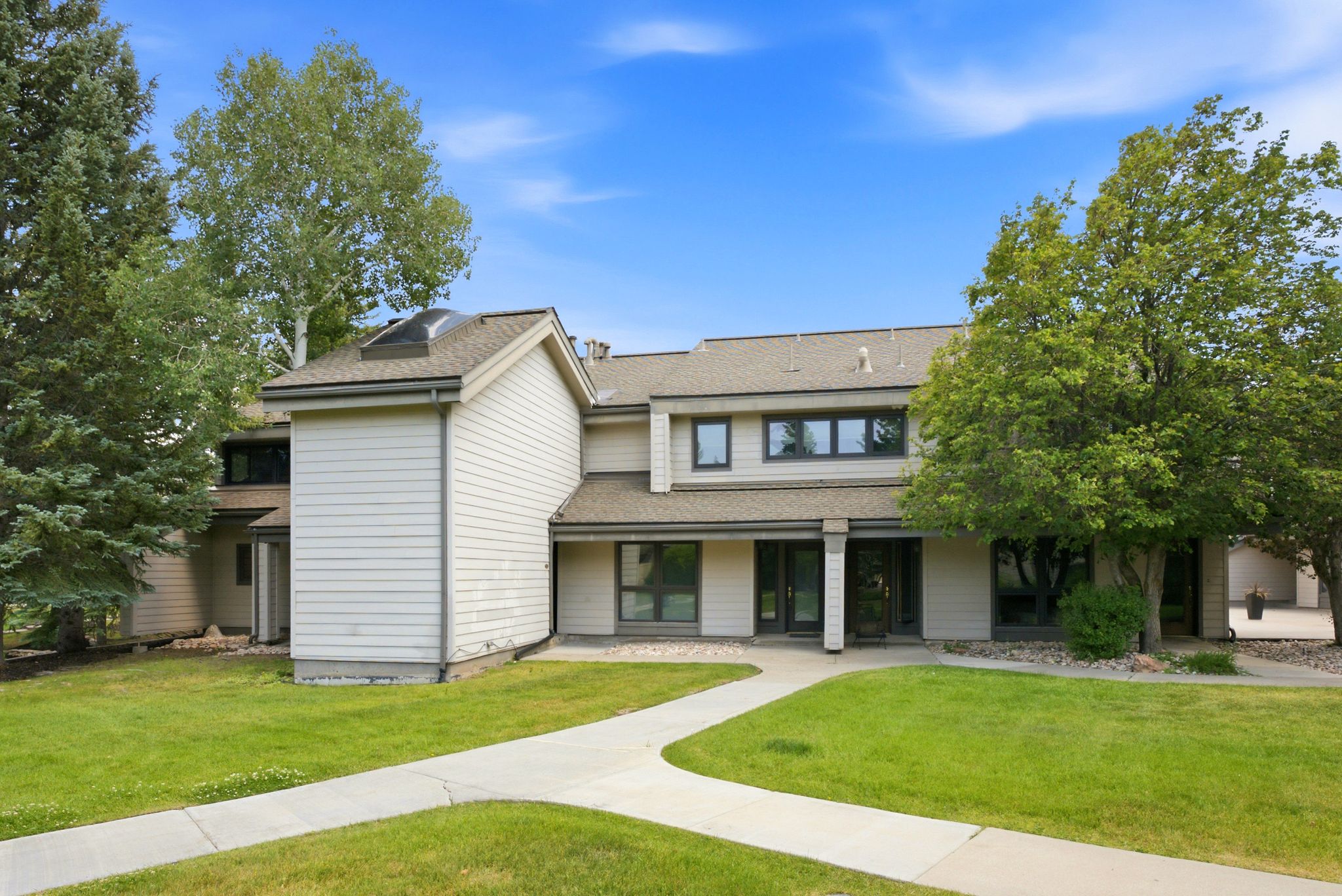 Multi-level residence featuring light-colored siding and a dark roofline
