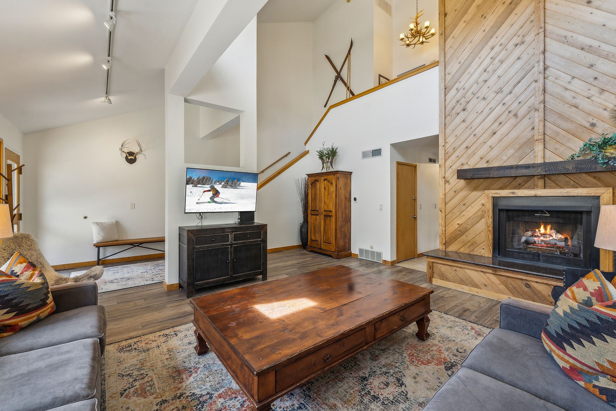 Living area featuring a floor-to-ceiling fireplace with diagonal wood paneling and a dark wood mantel