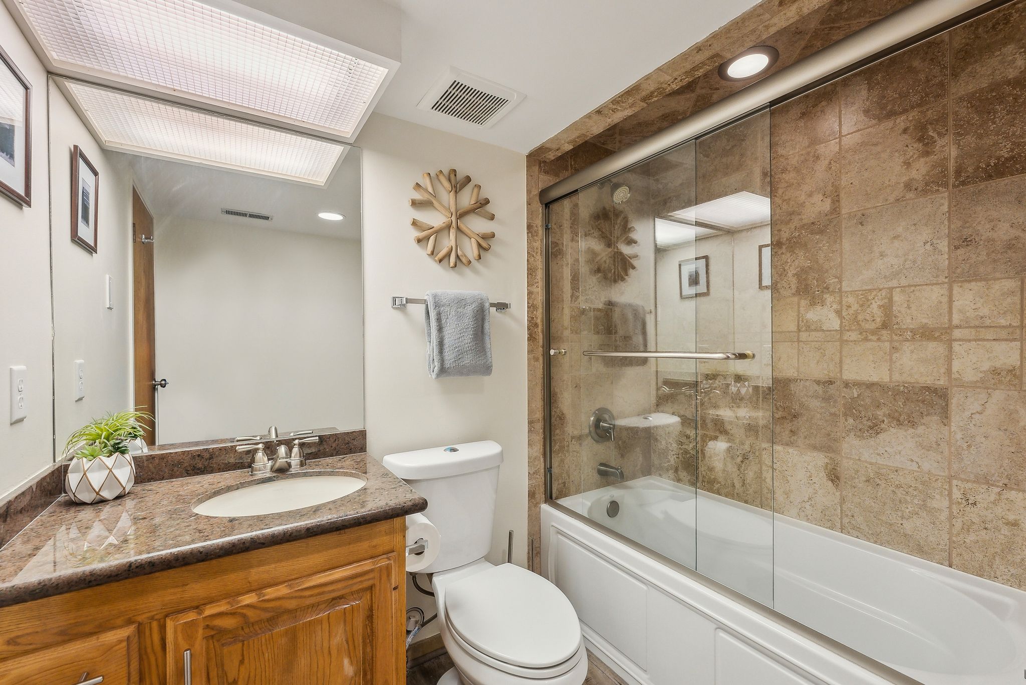 Bathroom featuring a wood-finish vanity with an undermount sink and granite-style countertop