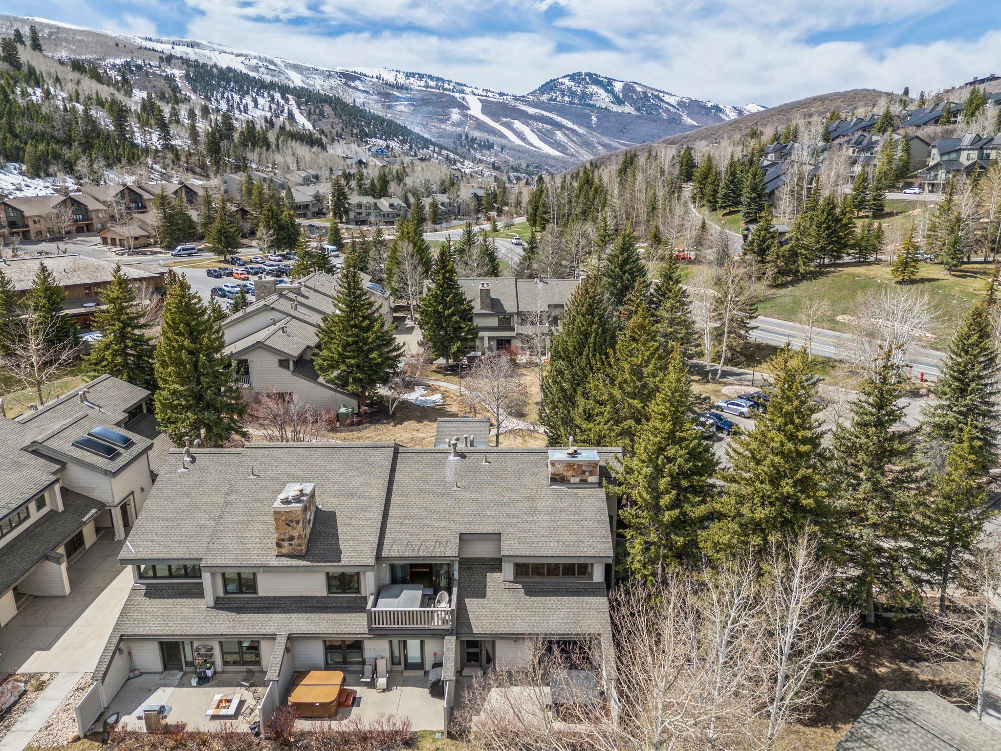 Townhome property featuring a private patio space, a second-story balcony, and a prominent stone chimney