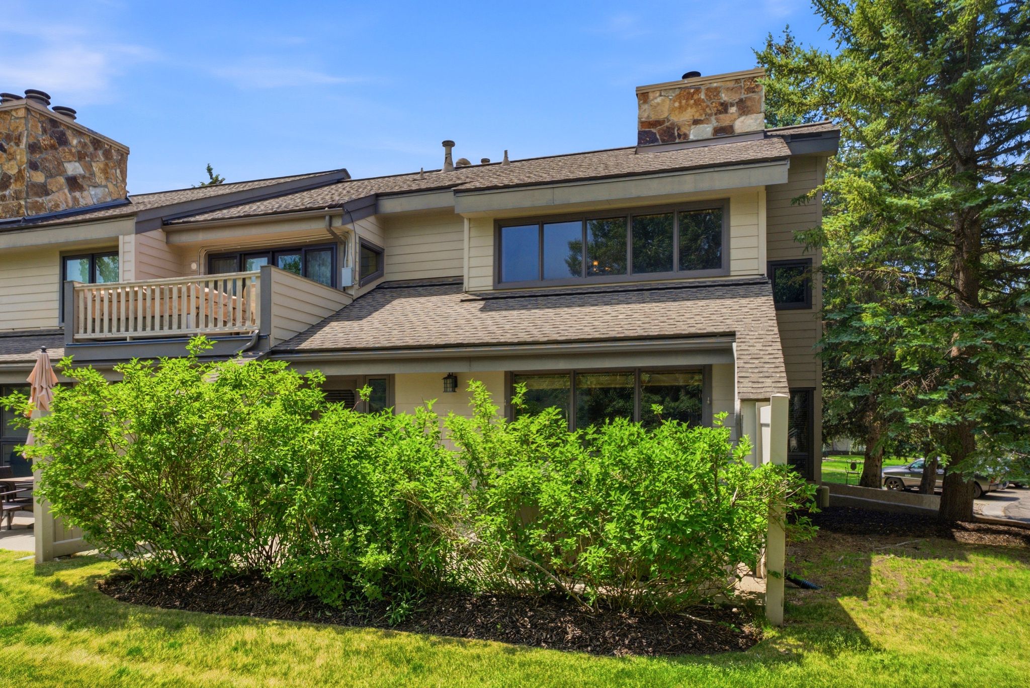 Multi-level property with stone chimney accents, horizontal siding, and a prominent balcony with wood railing