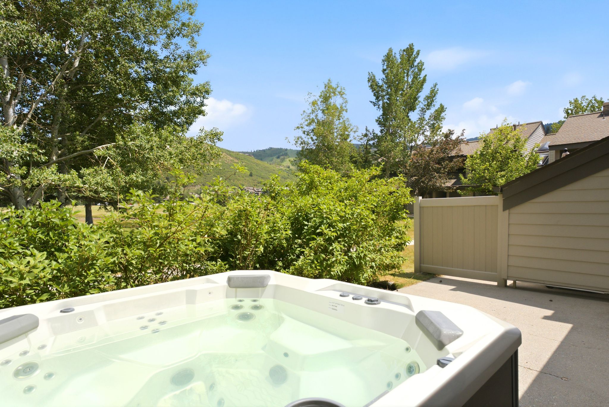 Outdoor hot tub with integrated seating, set on a concrete patio