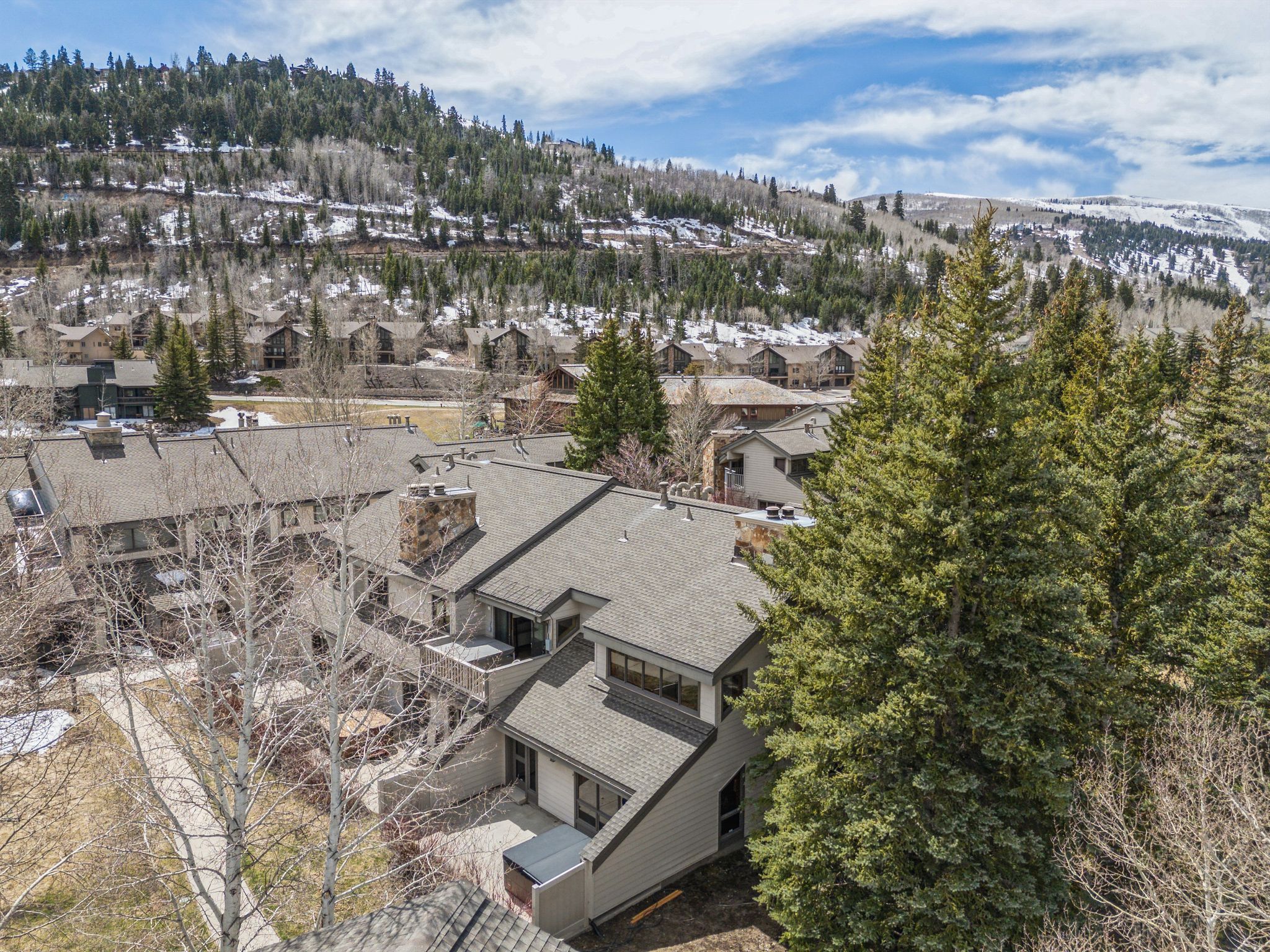 Multi-level property featuring a neutral exterior, stone chimney, and a durable shingle roof