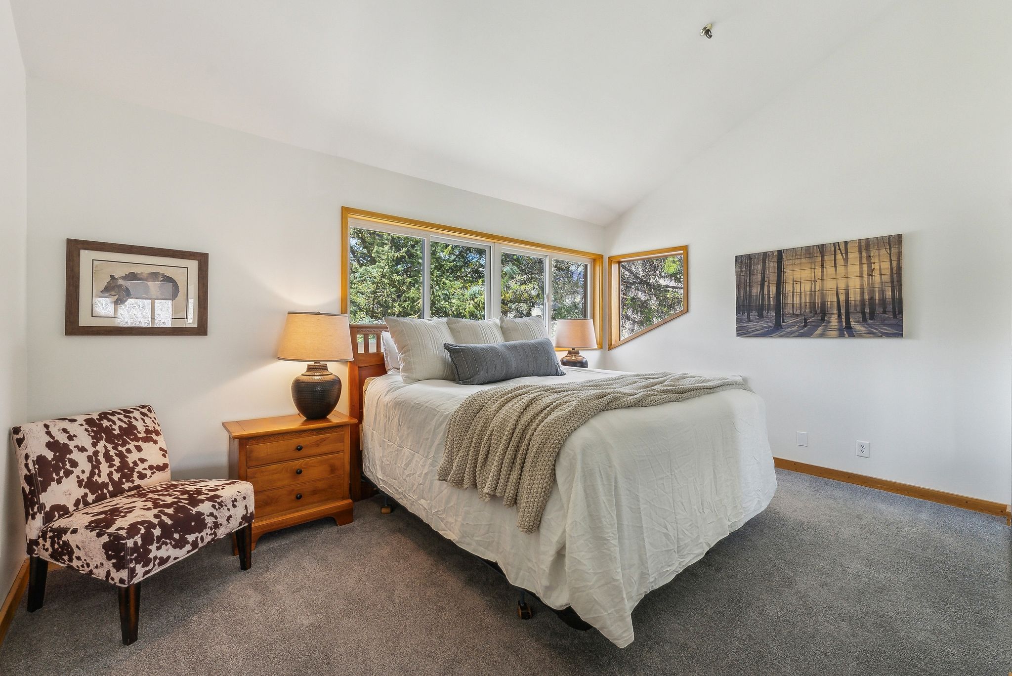 Vaulted ceilings accentuate the room, featuring expansive windows with wood trim