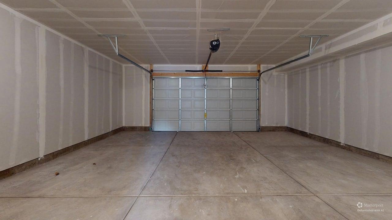 Spacious garage with a sectional overhead door and a ceiling-mounted opener