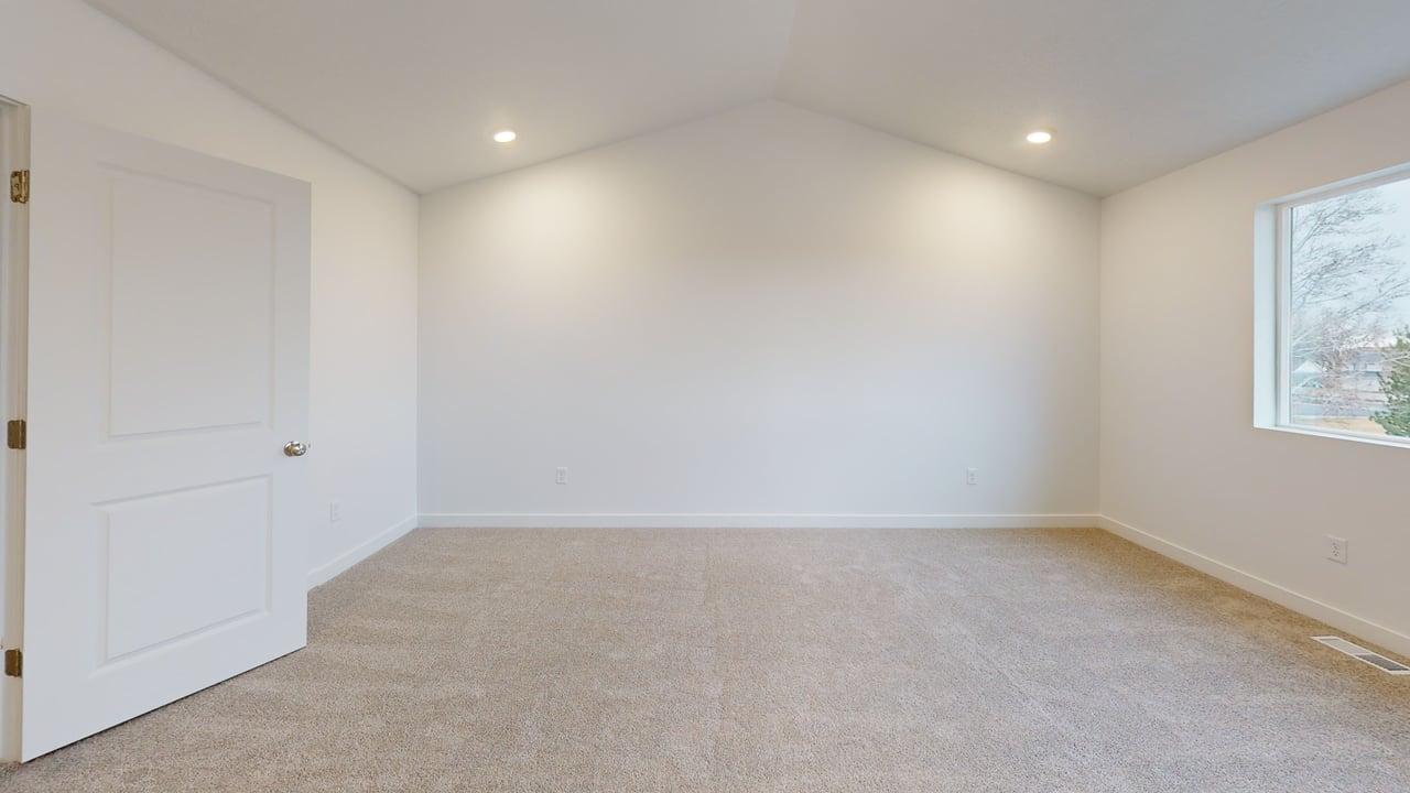 Spacious room featuring vaulted ceilings, light neutral carpeting, recessed lighting, and a single window with white trim