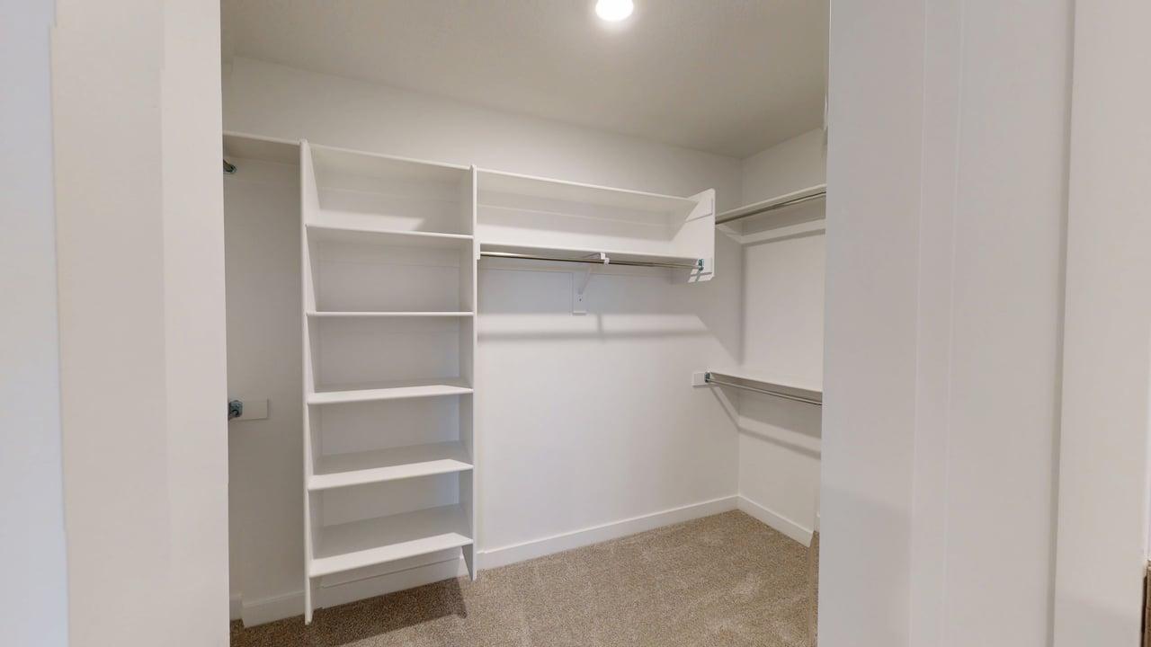 Walk-in closet featuring built-in shelving, multiple hanging rods, recessed ceiling lighting, and carpet flooring