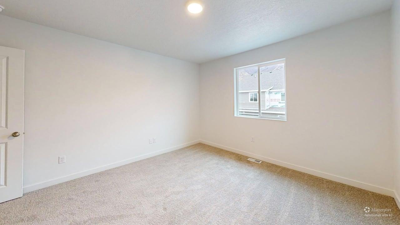 Carpeted room featuring a white interior door with a brass-finish knob, white baseboards, and a single window with white trim