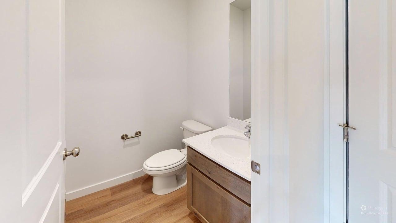 Powder room featuring a single vanity with an integrated sink, wood-finish flooring, and a wall-mounted mirror