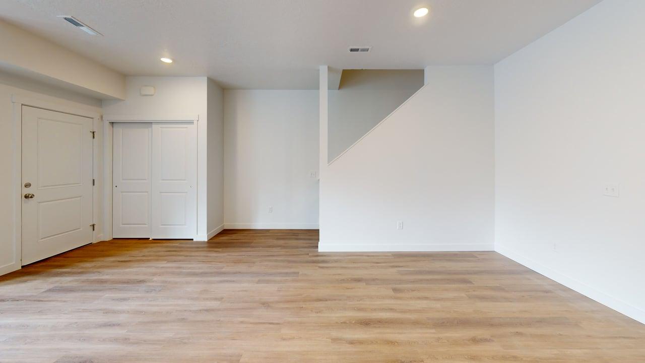 Spacious room featuring wood-finish flooring, recessed lighting, and bright white walls