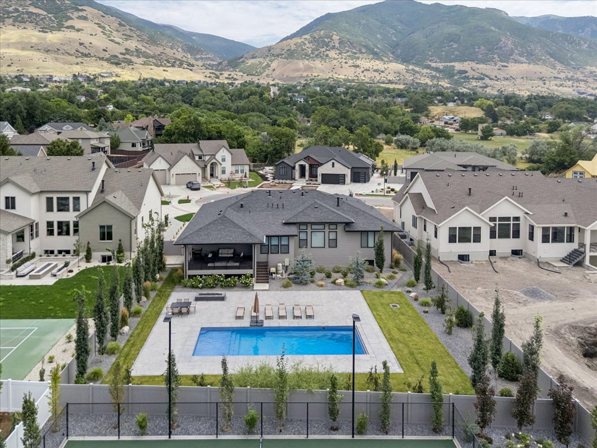 Expansive backyard featuring a large swimming pool with surrounding patio, a covered outdoor living area, and a dedicated tennis court