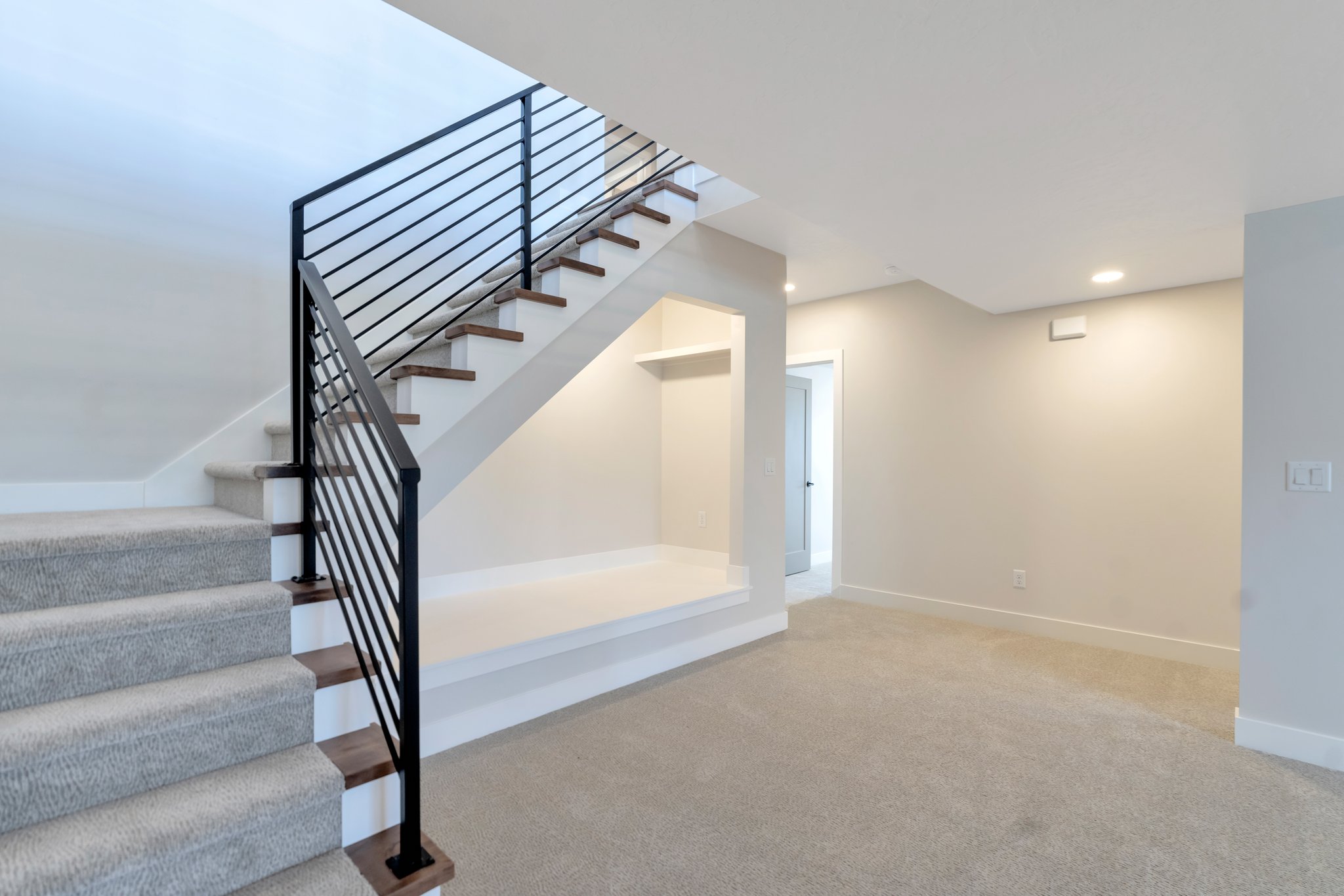 Modern staircase featuring a black metal railing and wood-finish treads