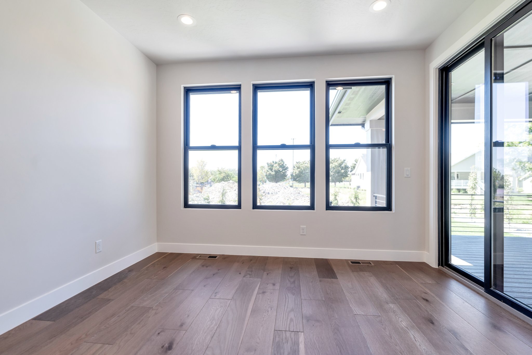 Spacious room featuring wood-finish flooring and a white baseboard trim