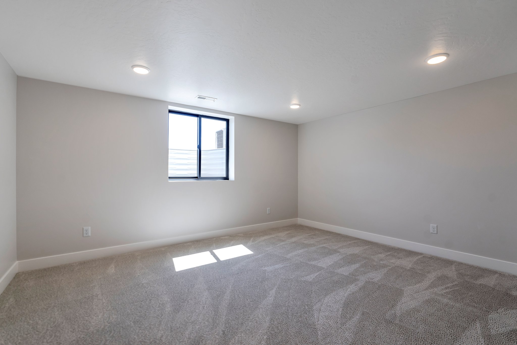 Spacious room featuring gray patterned carpeting and light gray walls