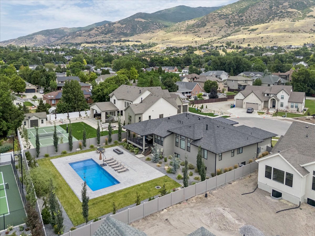 Property featuring a swimming pool, paved patio, full tennis court, expansive lawn, and mature landscaping
