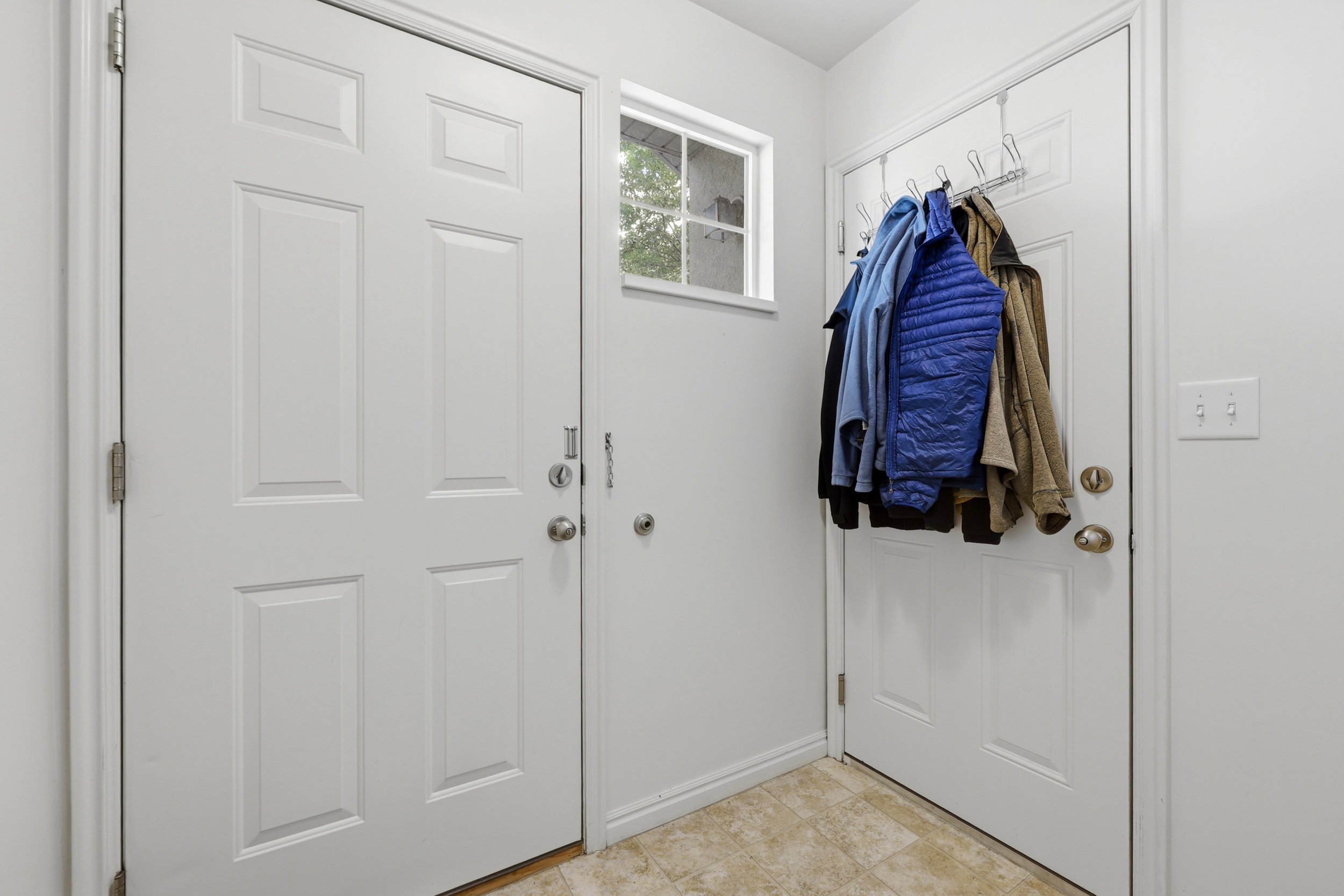 Entryway featuring two paneled doors, a transom window, light neutral wall paint, and tiled flooring