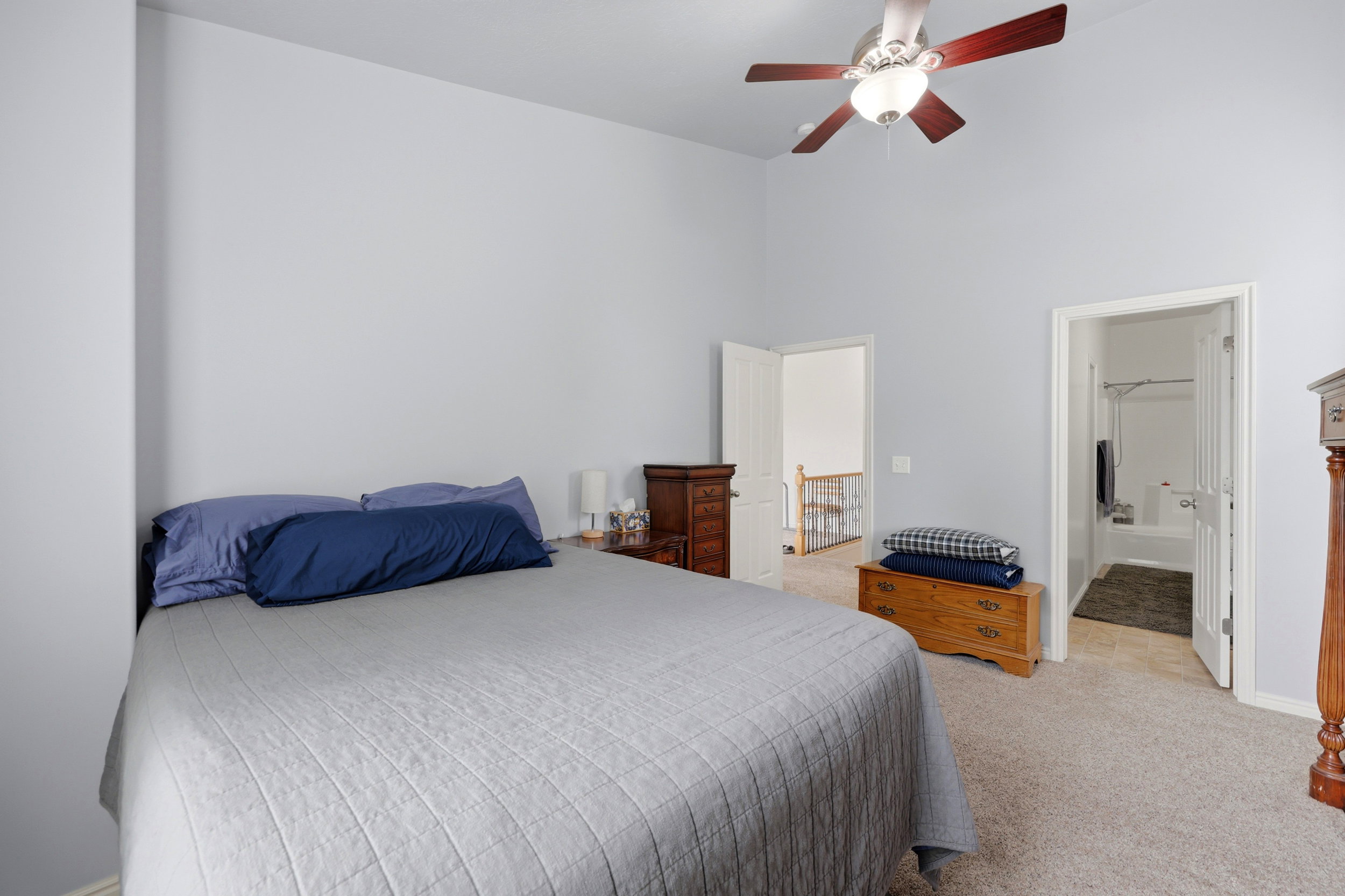 Carpeted bedroom with a vaulted ceiling and a ceiling fan with light fixture