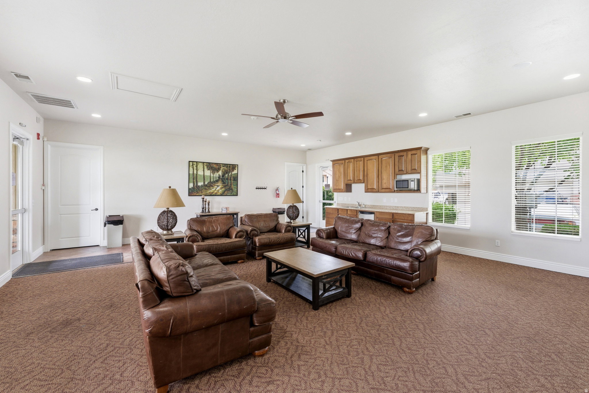 Spacious common area featuring textured carpeting, multiple recessed lights, and a ceiling fan