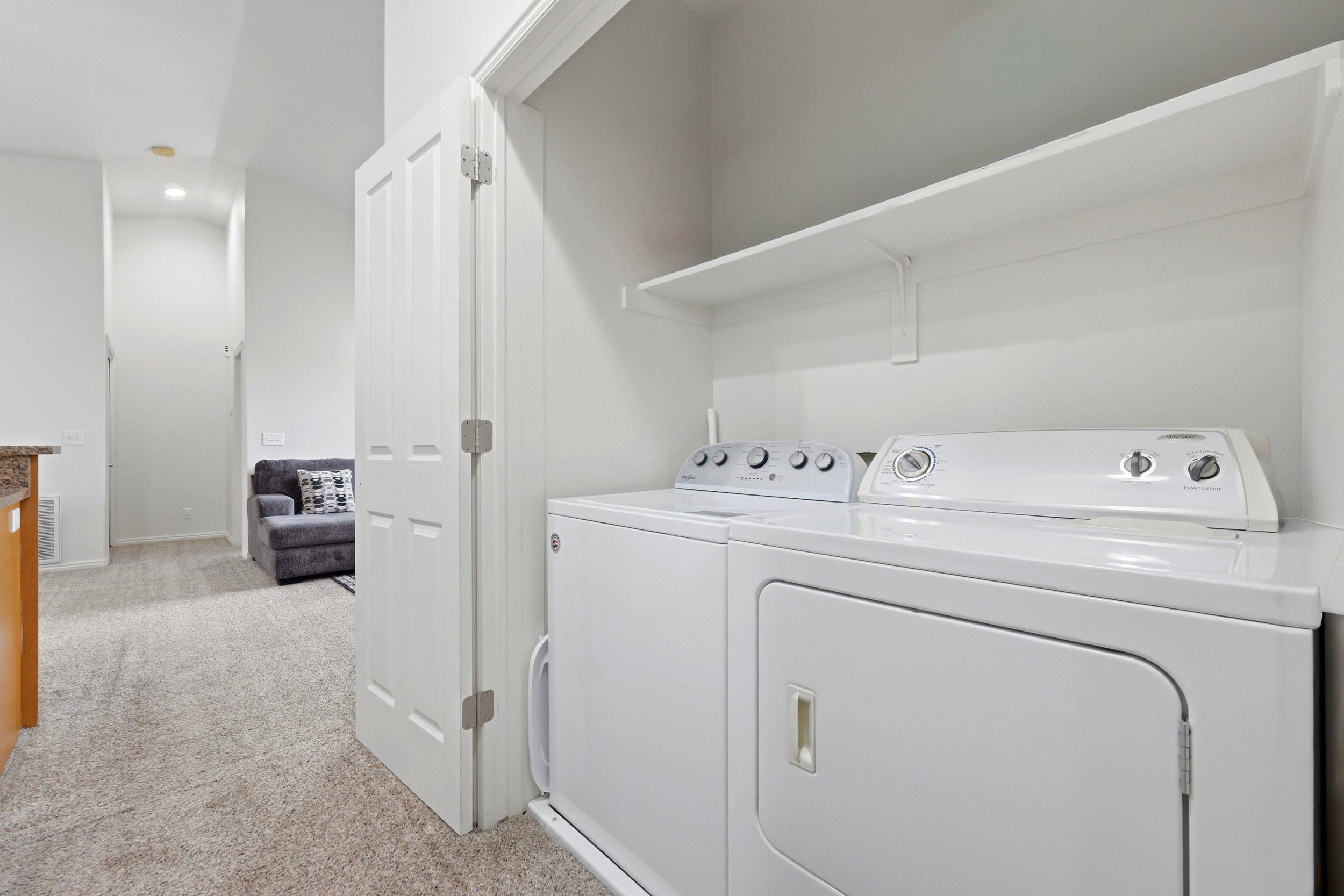 Dedicated laundry closet featuring a white washer and dryer pair, with an overhead white shelving unit