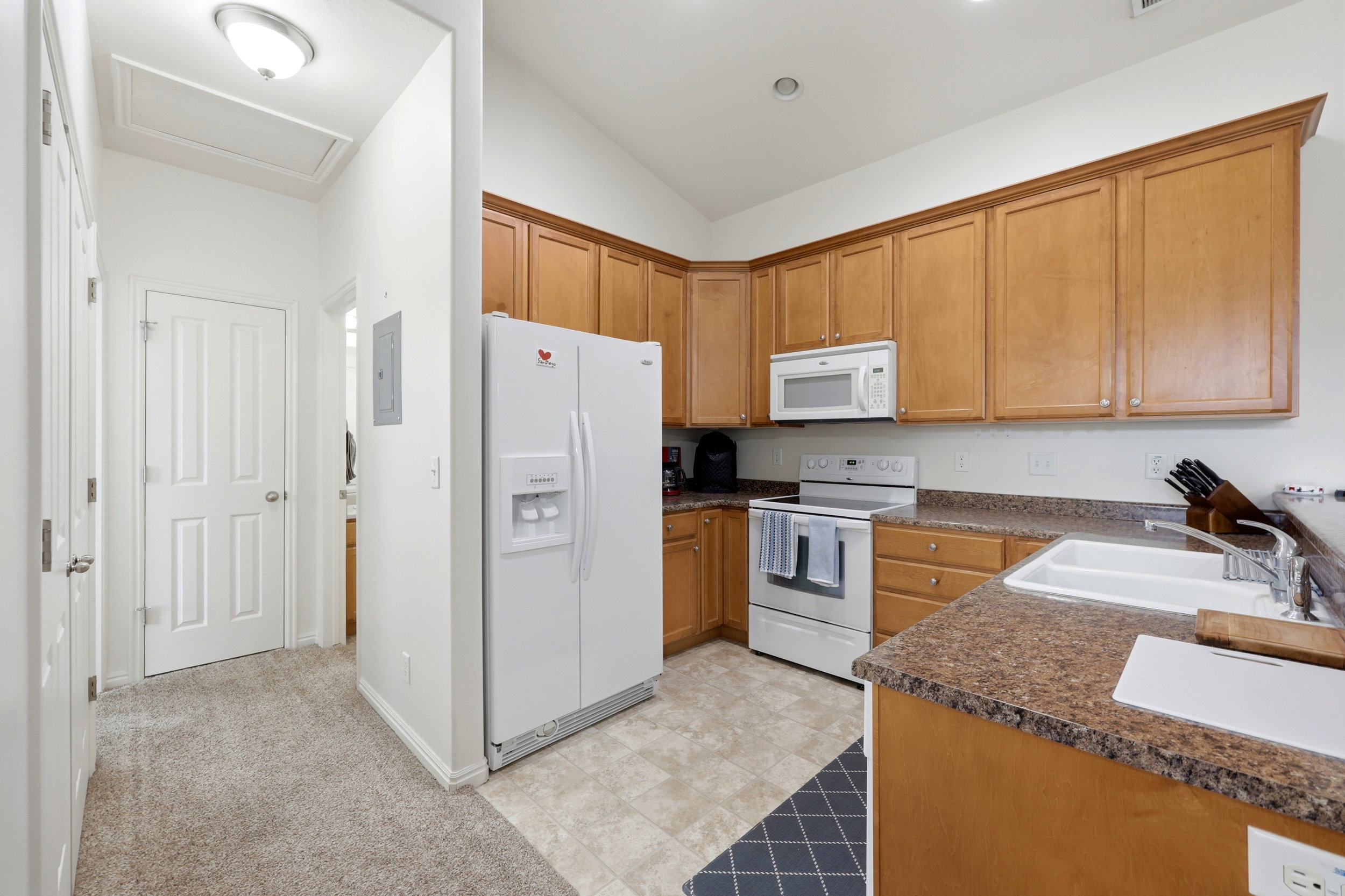 Kitchen featuring light wood cabinetry, white appliances, and a double basin sink