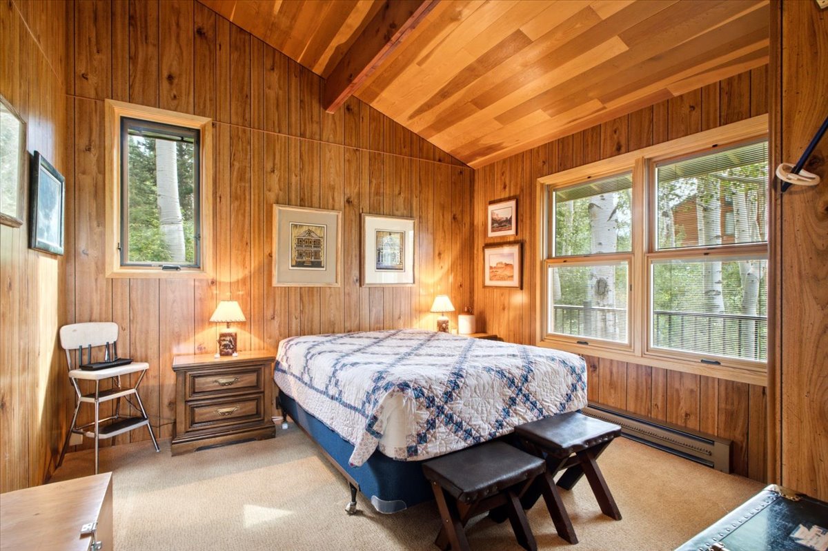 Wood-paneled room featuring a vaulted wood-finish ceiling with exposed beams