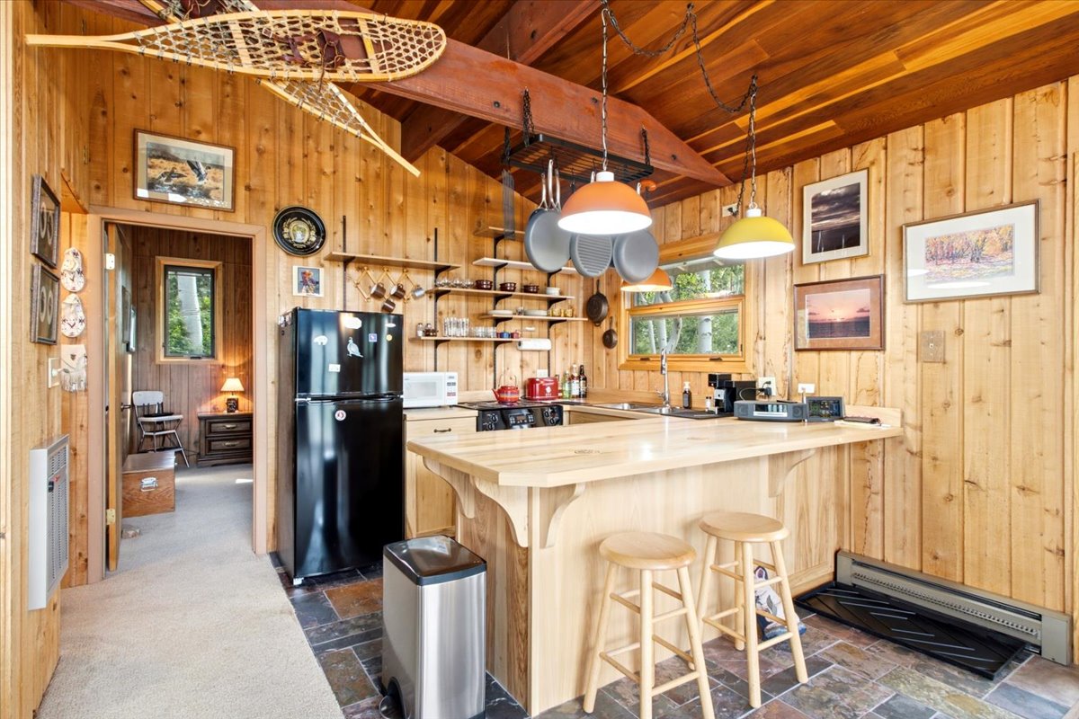 Kitchen with natural wood plank walls, a wood plank vaulted ceiling, and a slate-finish tile floor