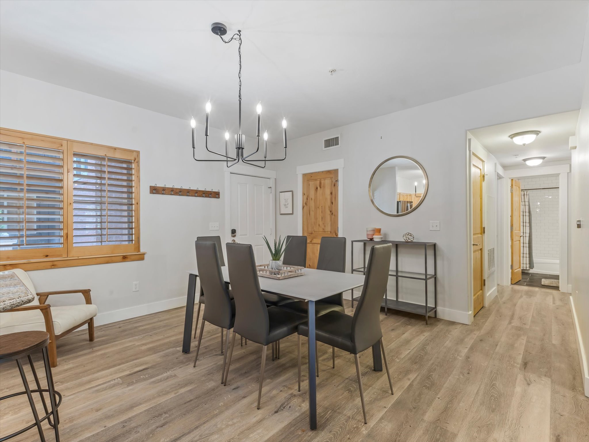Open-concept dining area featuring wood-finish flooring, a contemporary black chandelier, and light-toned walls