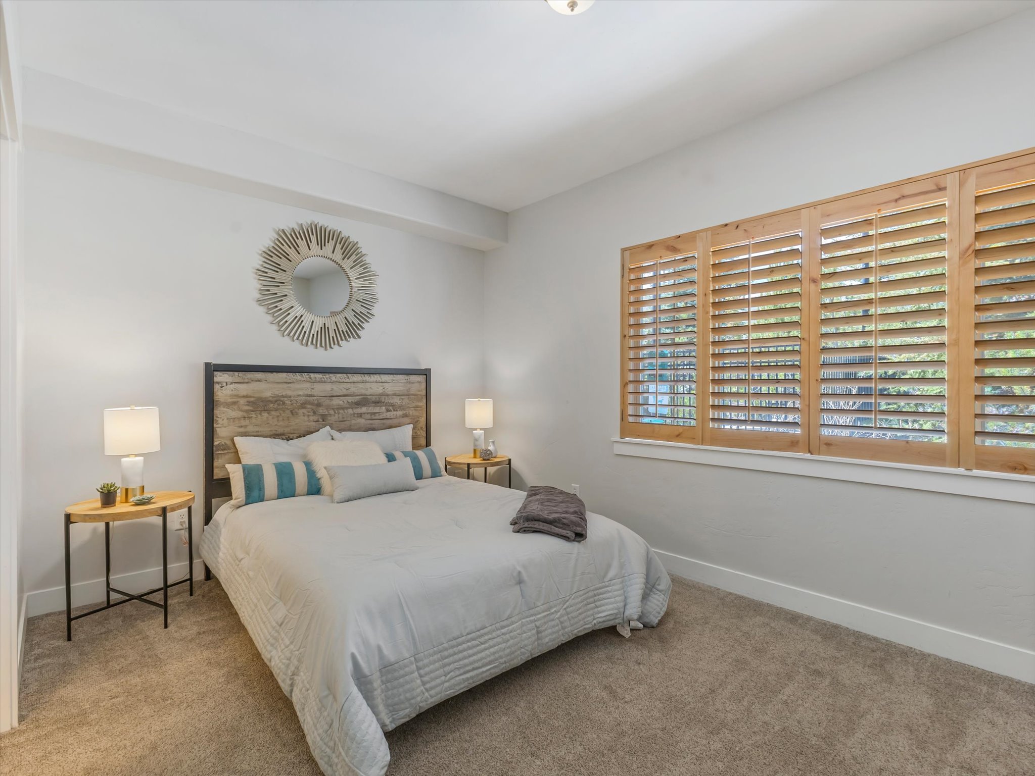 Carpeted bedroom featuring light-colored walls and wood-finish window shutters