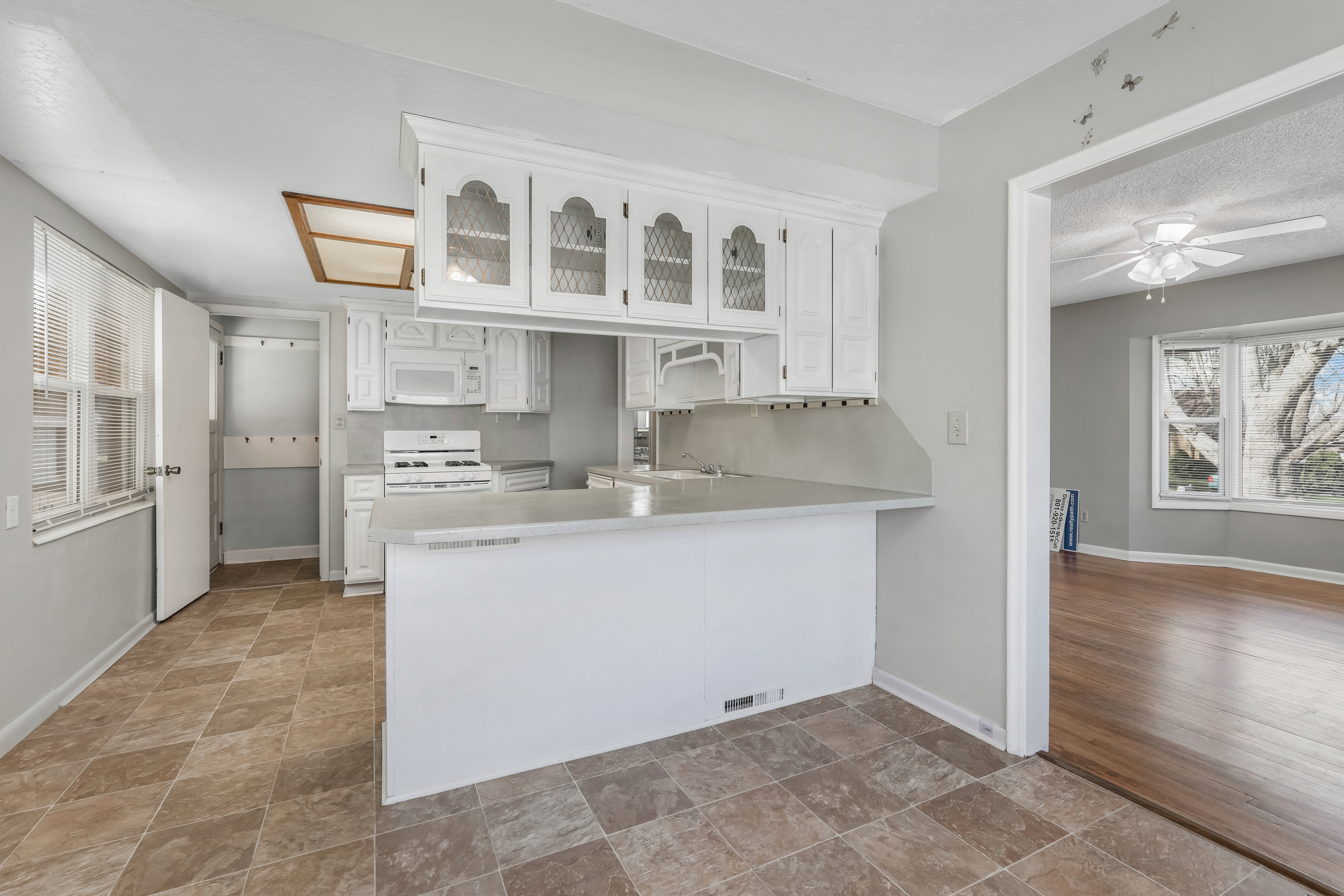Kitchen featuring white cabinetry, a built-in microwave, a gas range, a breakfast bar, and tiled flooring