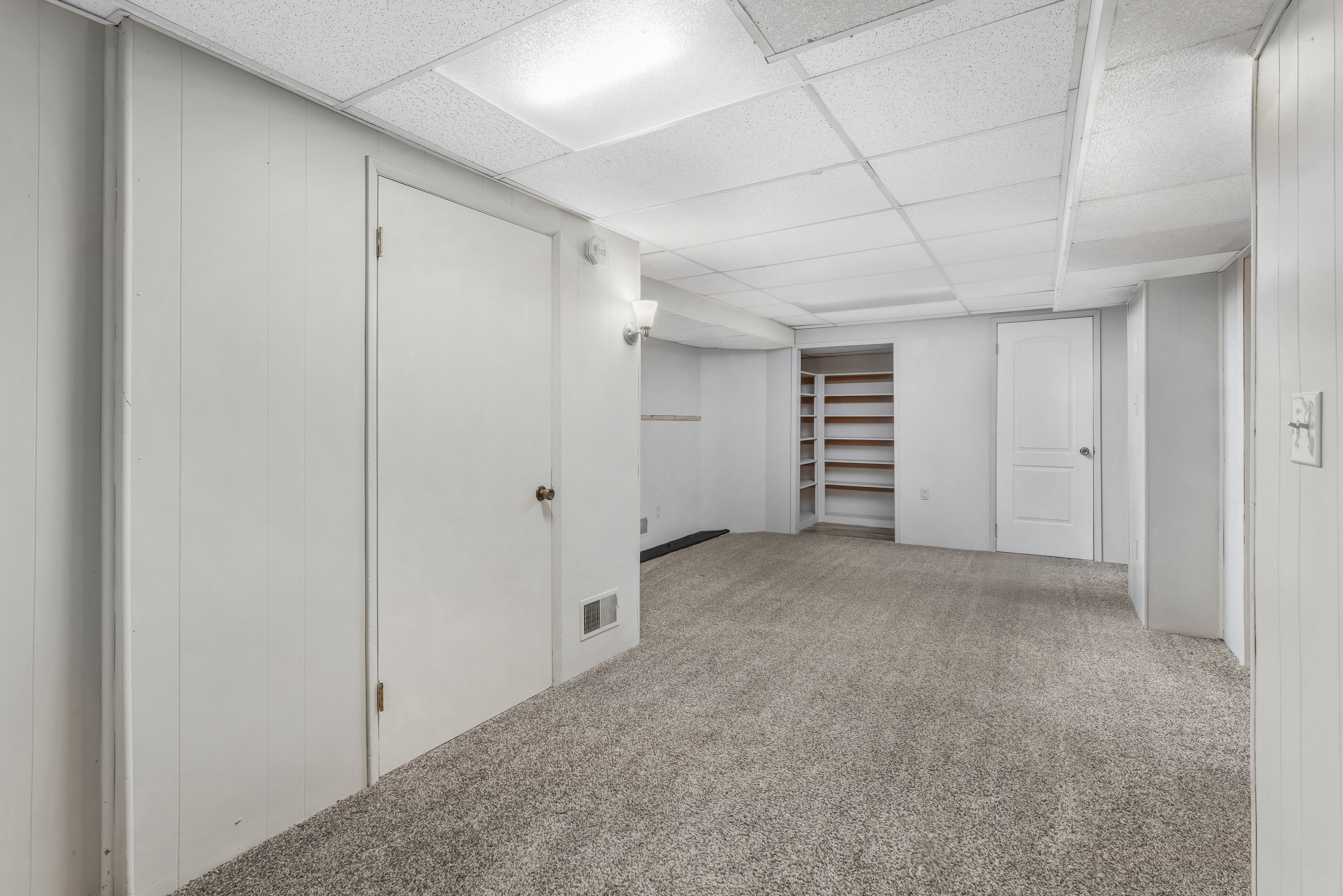 Carpeted room featuring white paneled walls and a drop ceiling