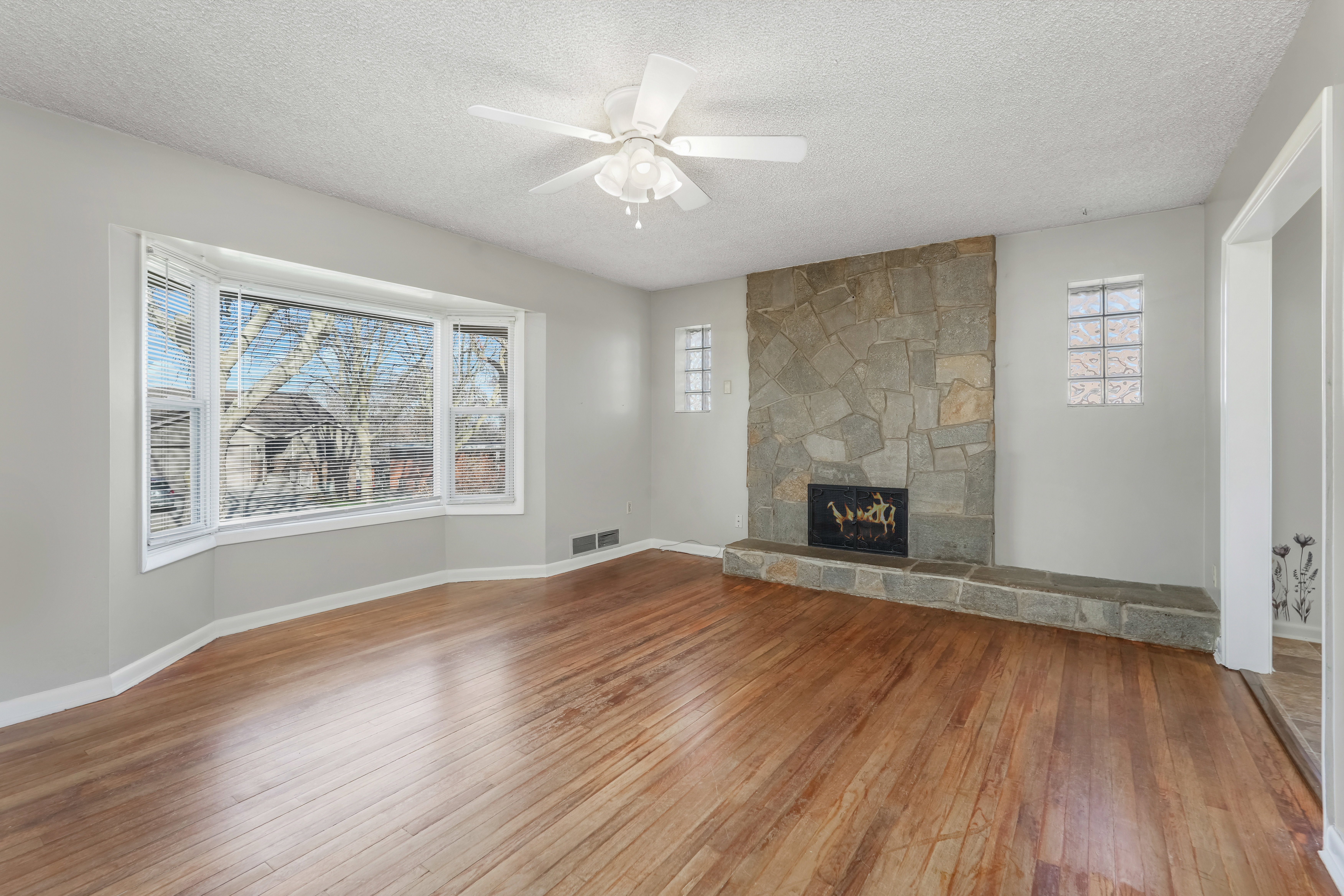 Hardwood flooring and a stone-clad fireplace with a matching hearth