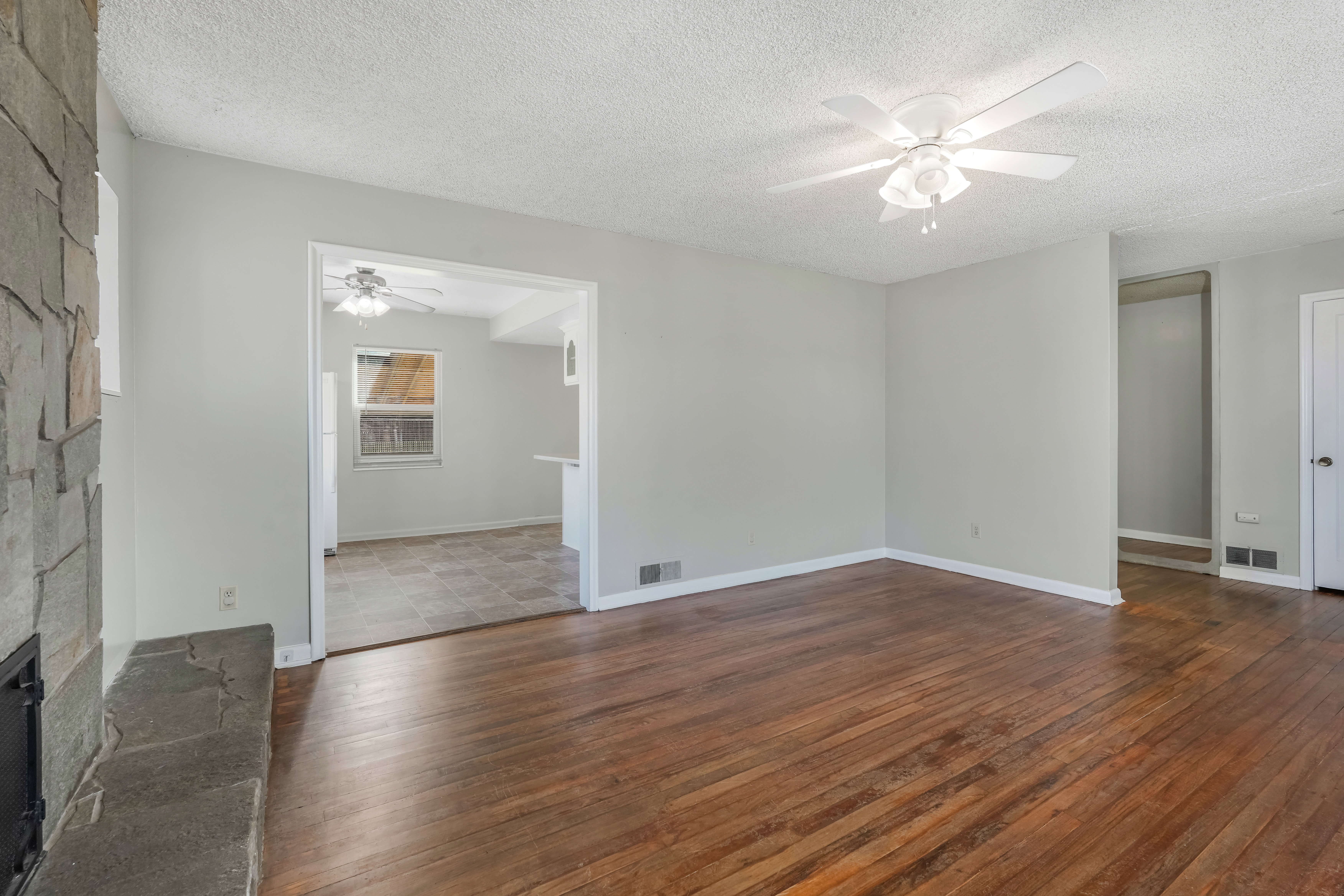 Spacious living area featuring rich wood-finish flooring and light gray walls