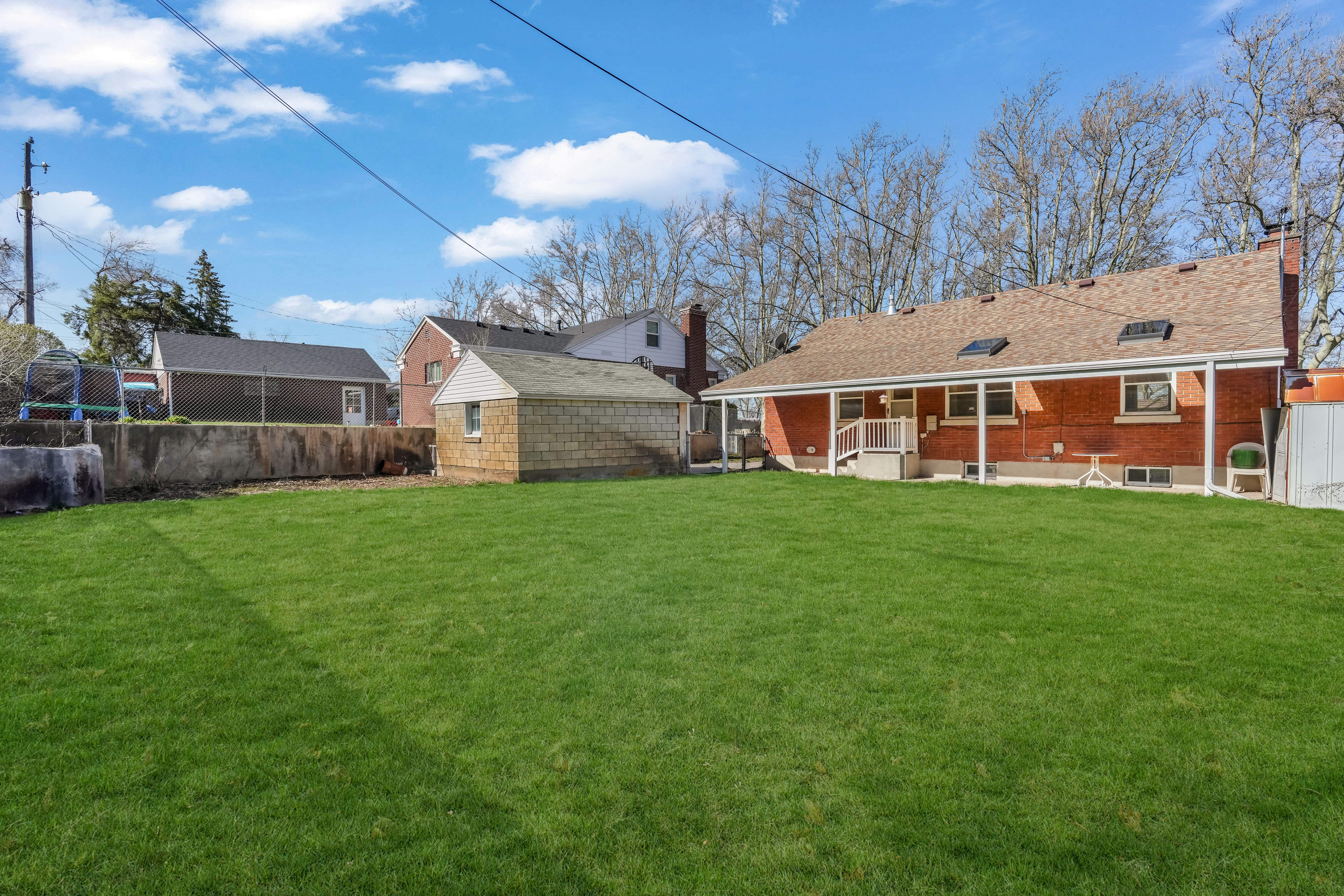 Expansive green lawn with a detached auxiliary building featuring block construction