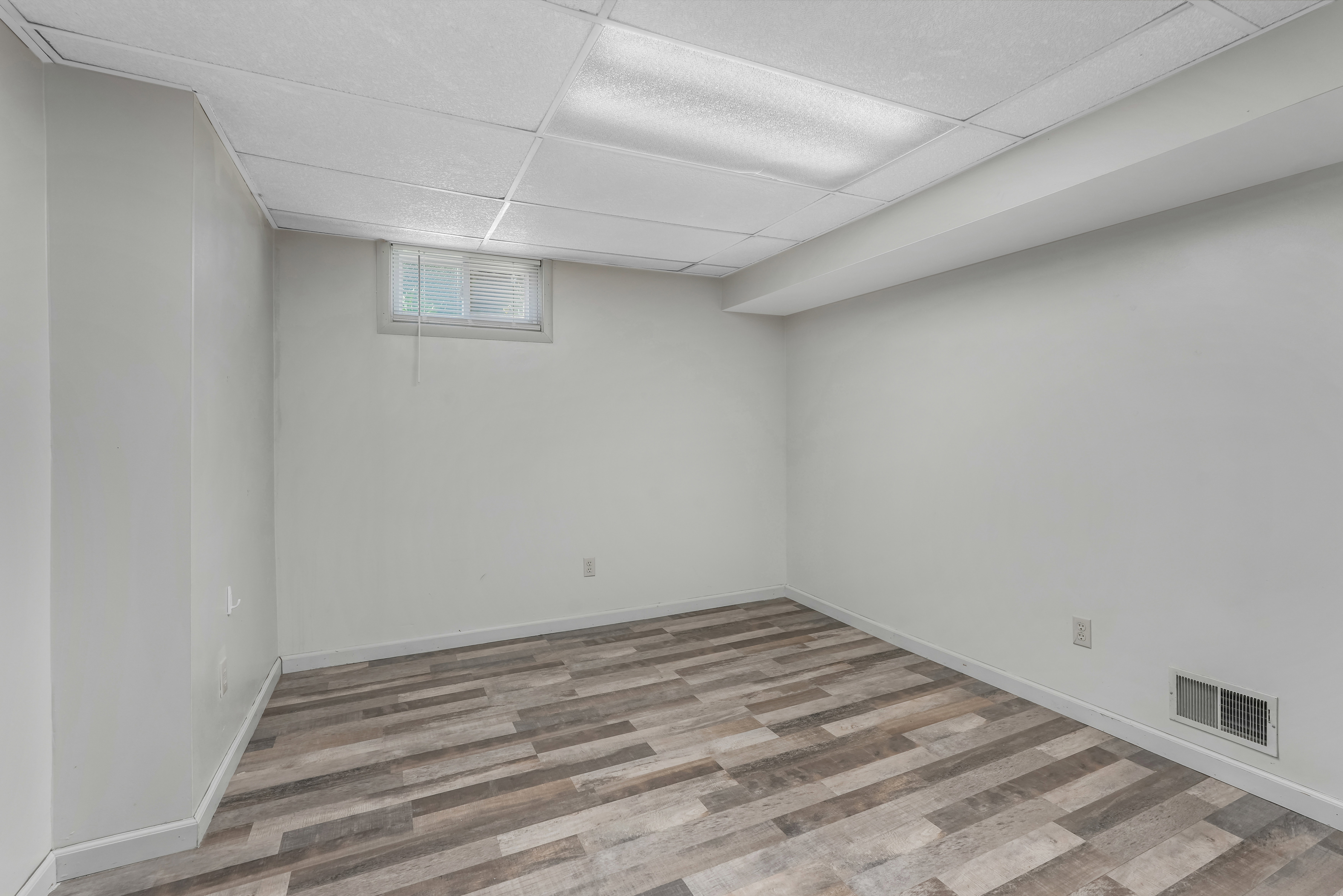 Room featuring wood-finish flooring, white baseboards, and neutral wall paint