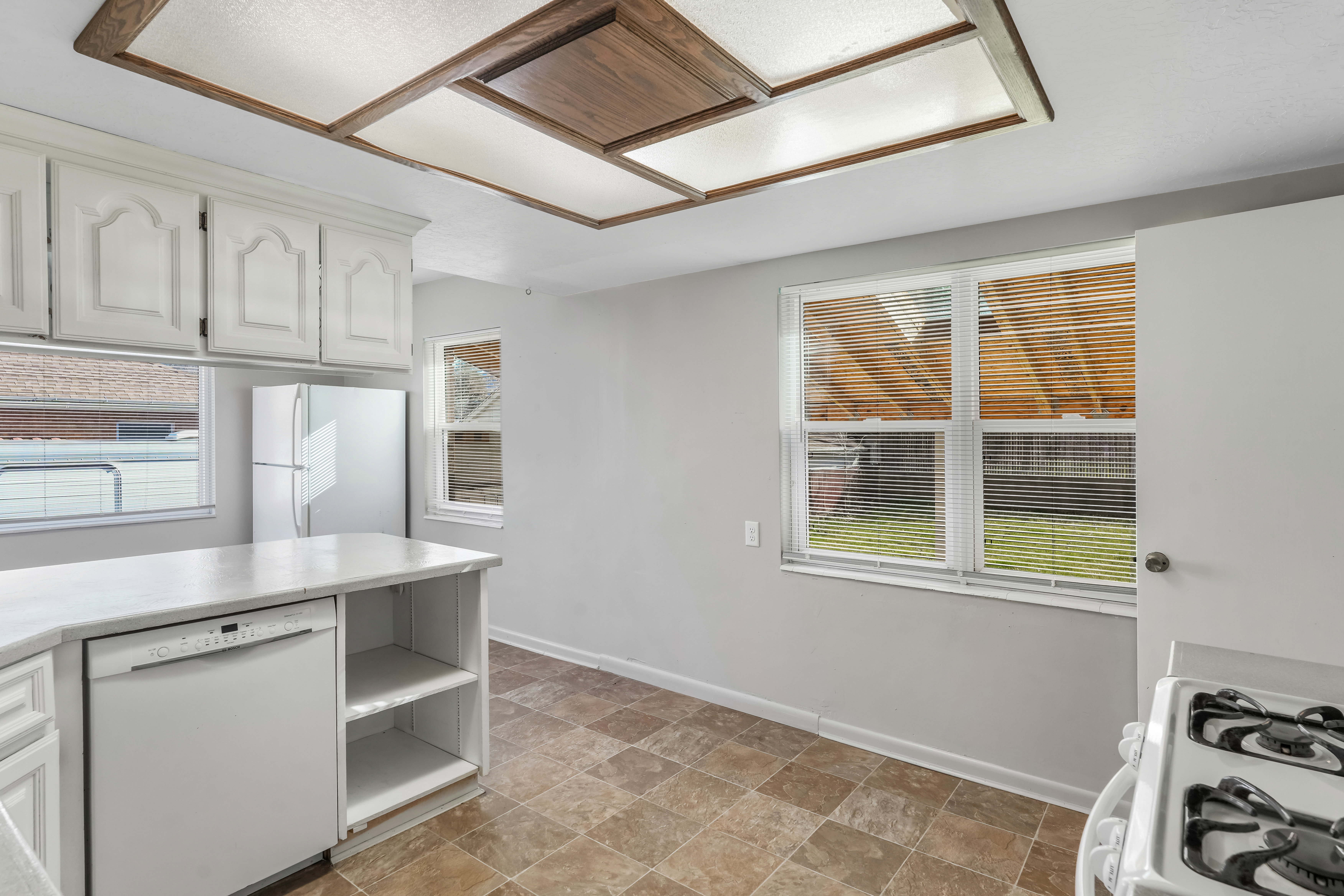 Kitchen featuring white cabinetry, a built-in dishwasher, an integrated refrigerator, a gas range, and a tiled ceiling light fixture