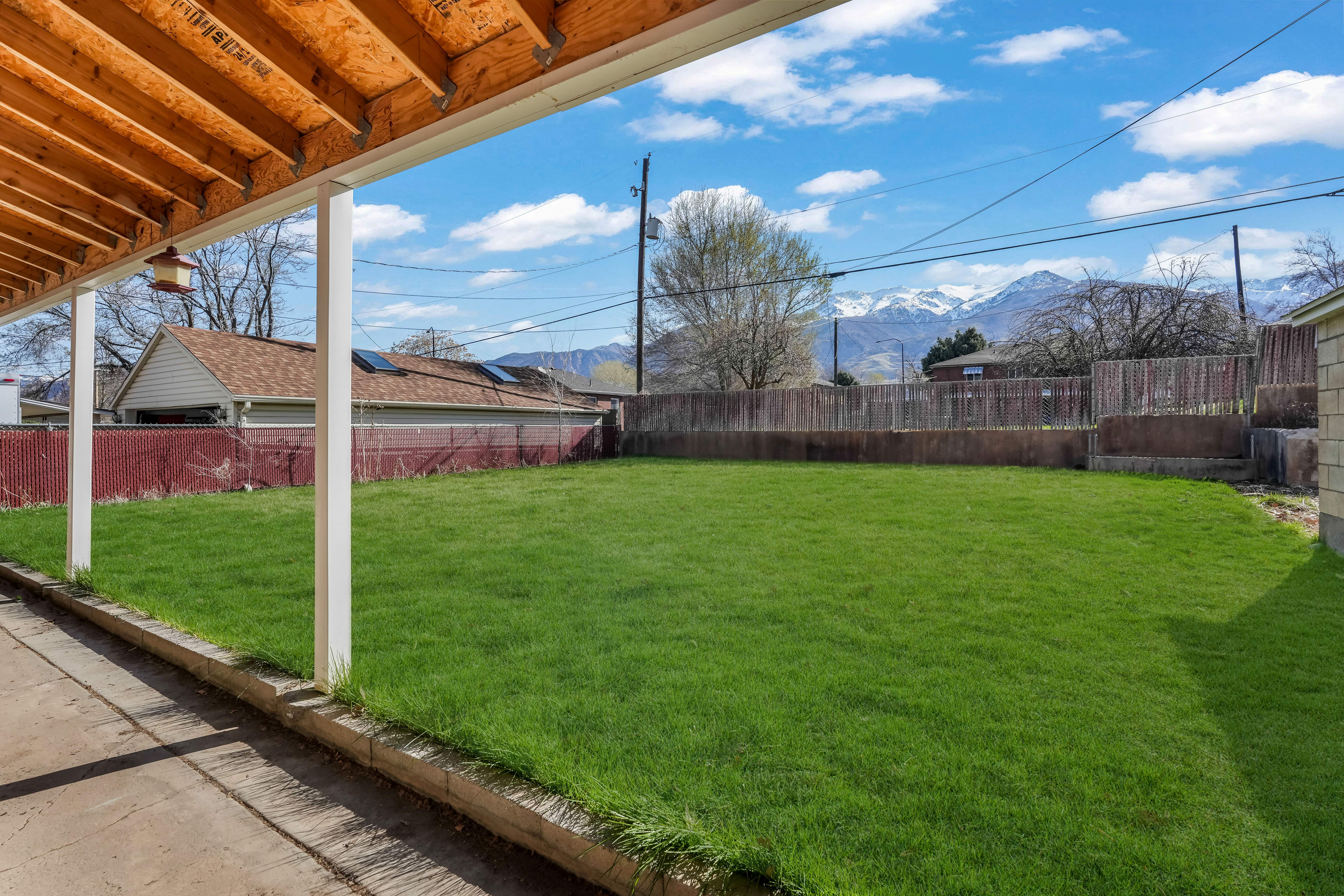 Expansive green lawn framed by a concrete patio and a slatted wooden fence